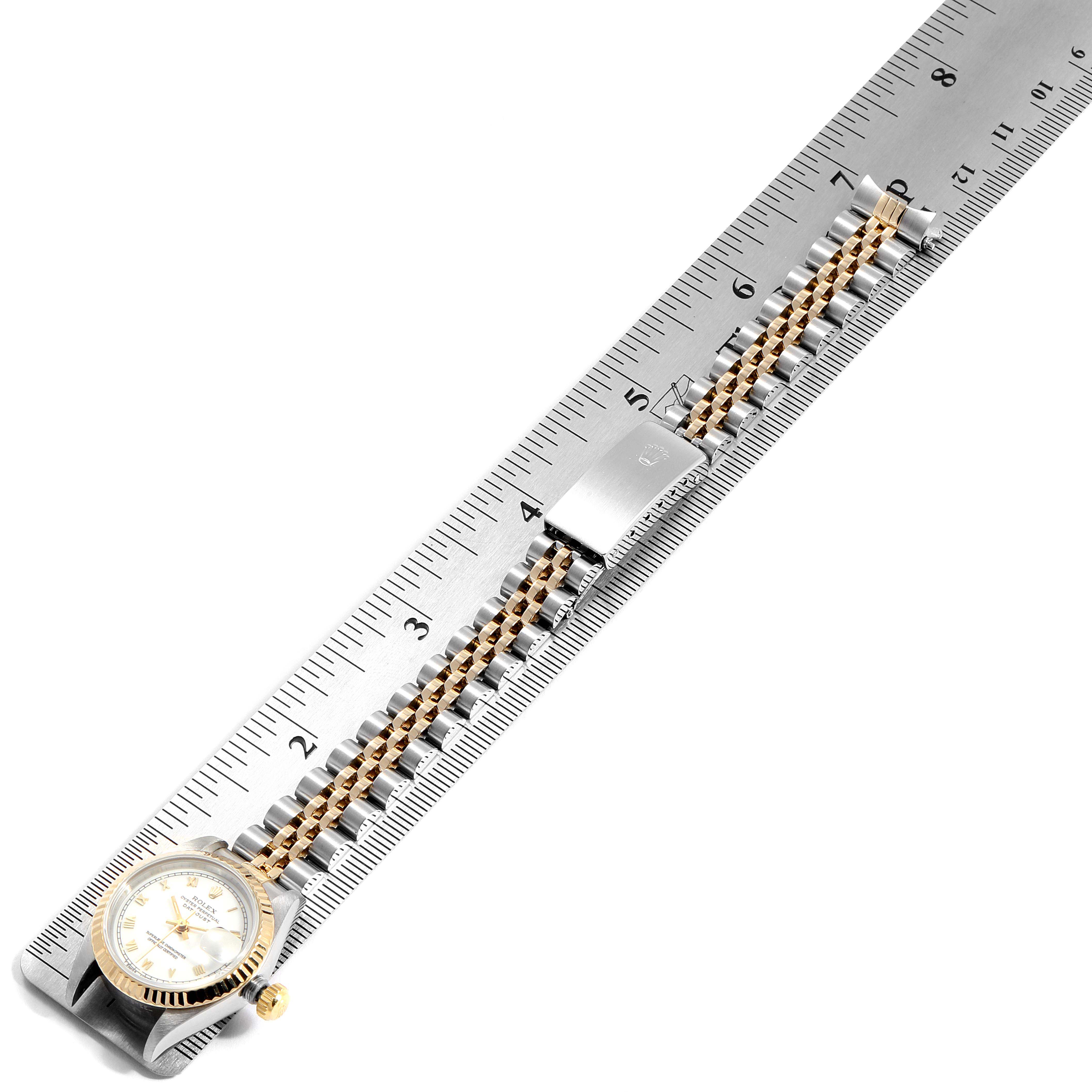 The Rolex Datejust 69173 Women
s Steel and Gold (two tone) White Dial 69173 Women
s Steel and Gold (two tone) White Dial watch is shown from a top-down angle, highlighting its face, bracelet, and clasp beside a ruler.