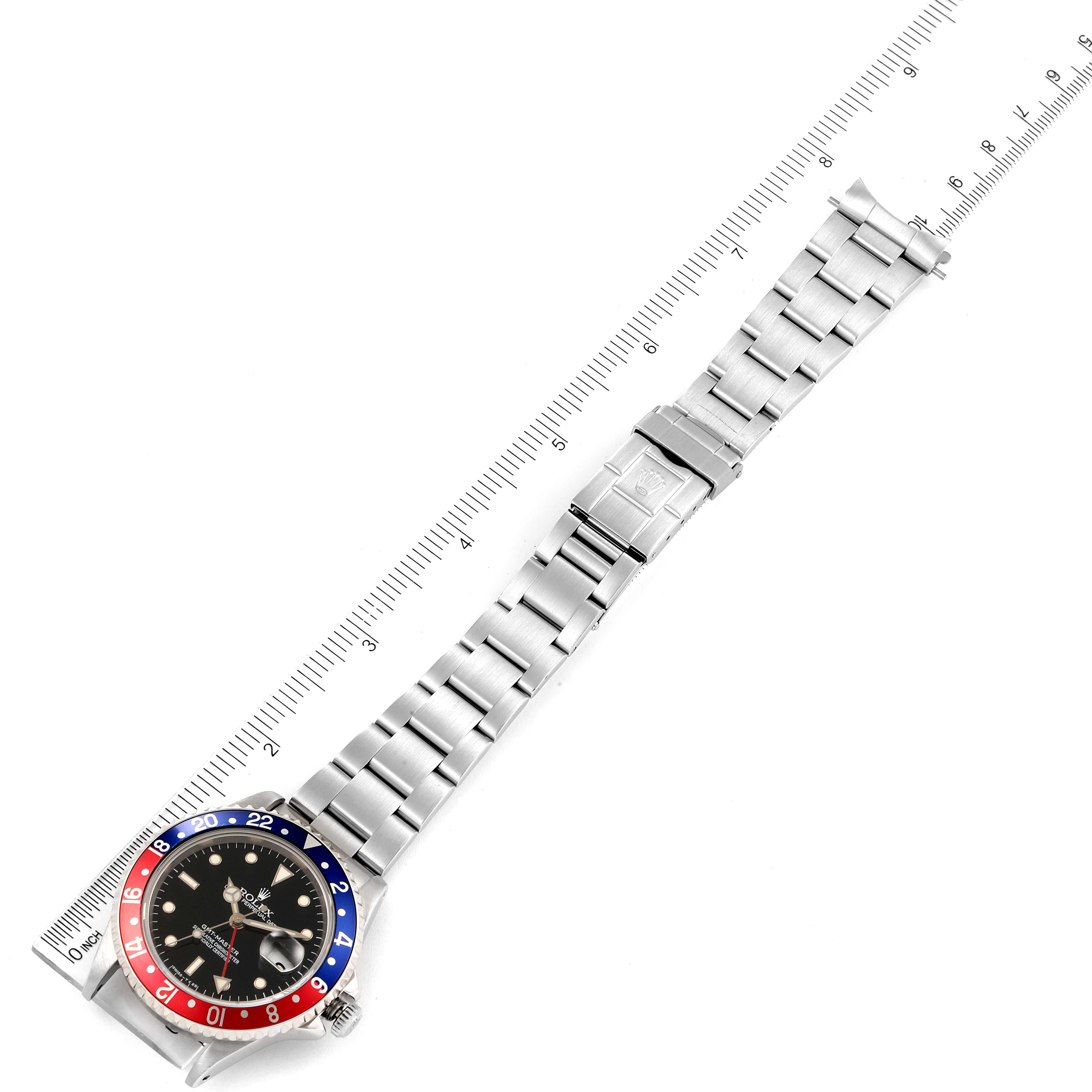 The image shows a top-down view of a Rolex GMT-Master 16700 Men's Stainless Steel Black Dial 16700 Men's Stainless Steel Black Dial watch, displaying the watch face, bezel, and stainless steel bracelet next to a ruler.