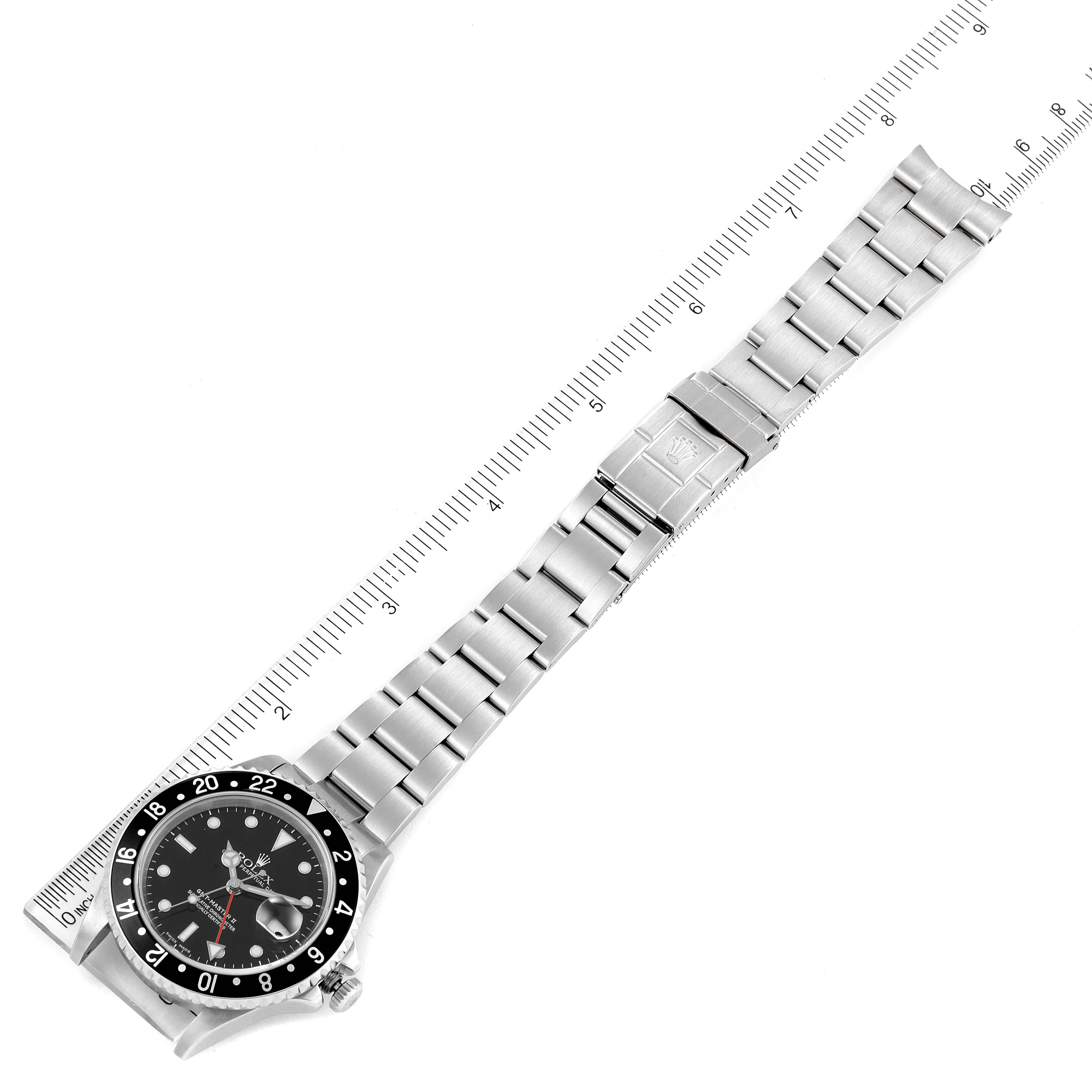 The Rolex GMT-Master 16710 Men
s Stainless Steel Black Dial 16710 Men
s Stainless Steel Black Dial watch is shown from above, featuring the face, bezel, and stainless steel bracelet laid next to a ruler.