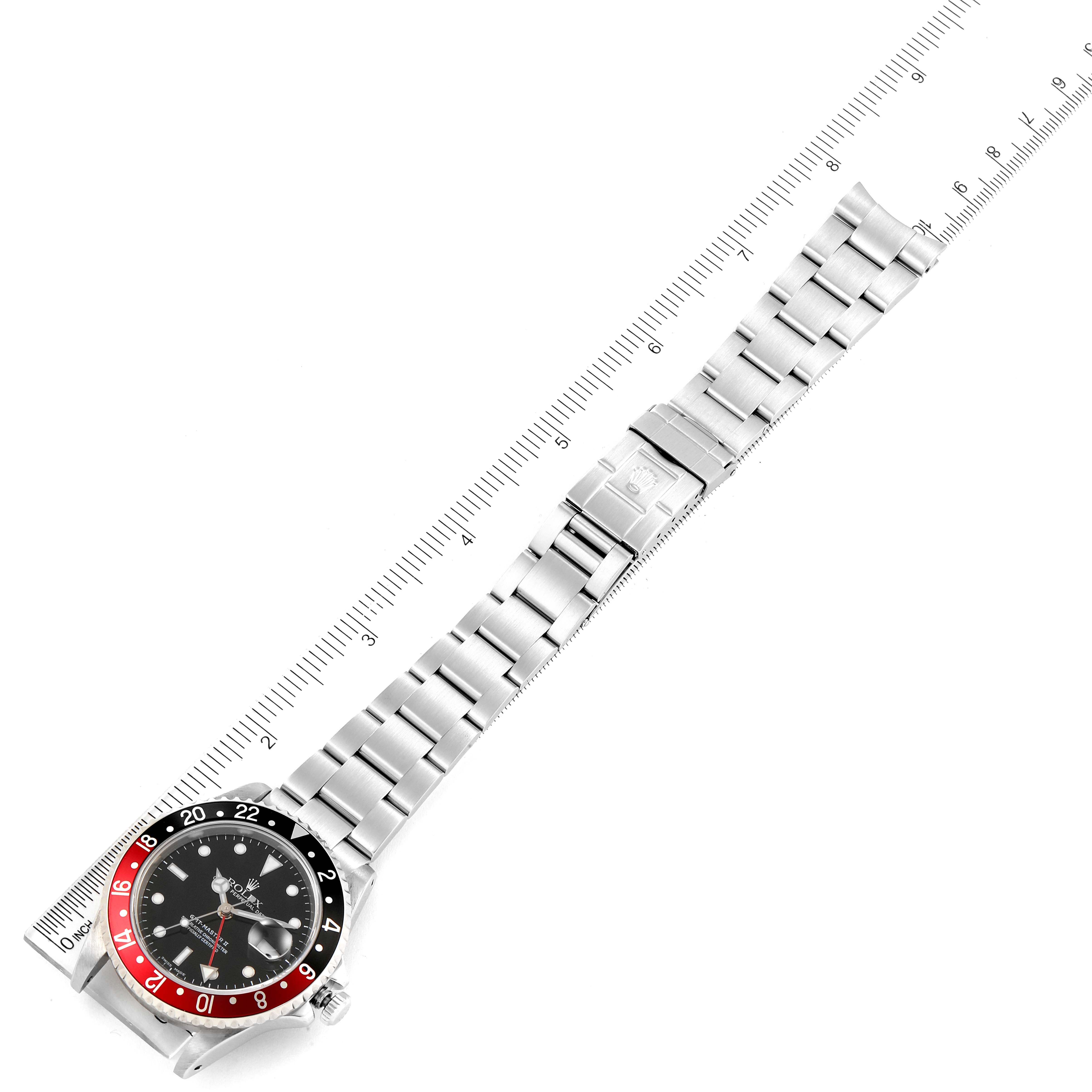 The image shows a top-down view of a Rolex GMT-Master 16710 Men
s Stainless Steel Black Dial 16710 Men
s Stainless Steel Black Dial watch, featuring the watch face, bezel, and bracelet alongside a ruler for scale.