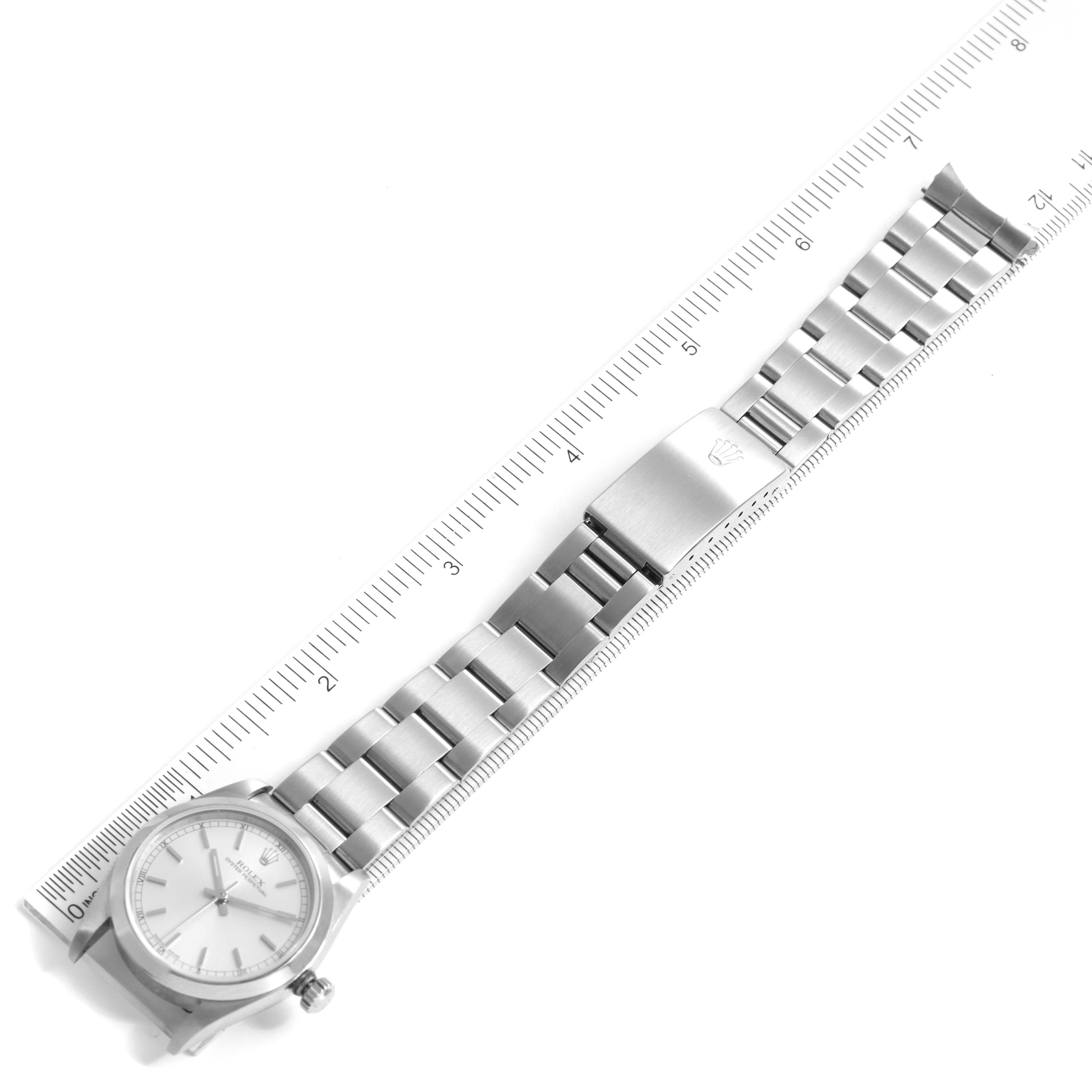 The image shows a Rolex Mid-Size 77080 Women's Stainless Steel Silver Dial 77080 Women's Stainless Steel Silver Dial model watch laid flat next to a ruler, displaying the watch face and metal bracelet with clasp.