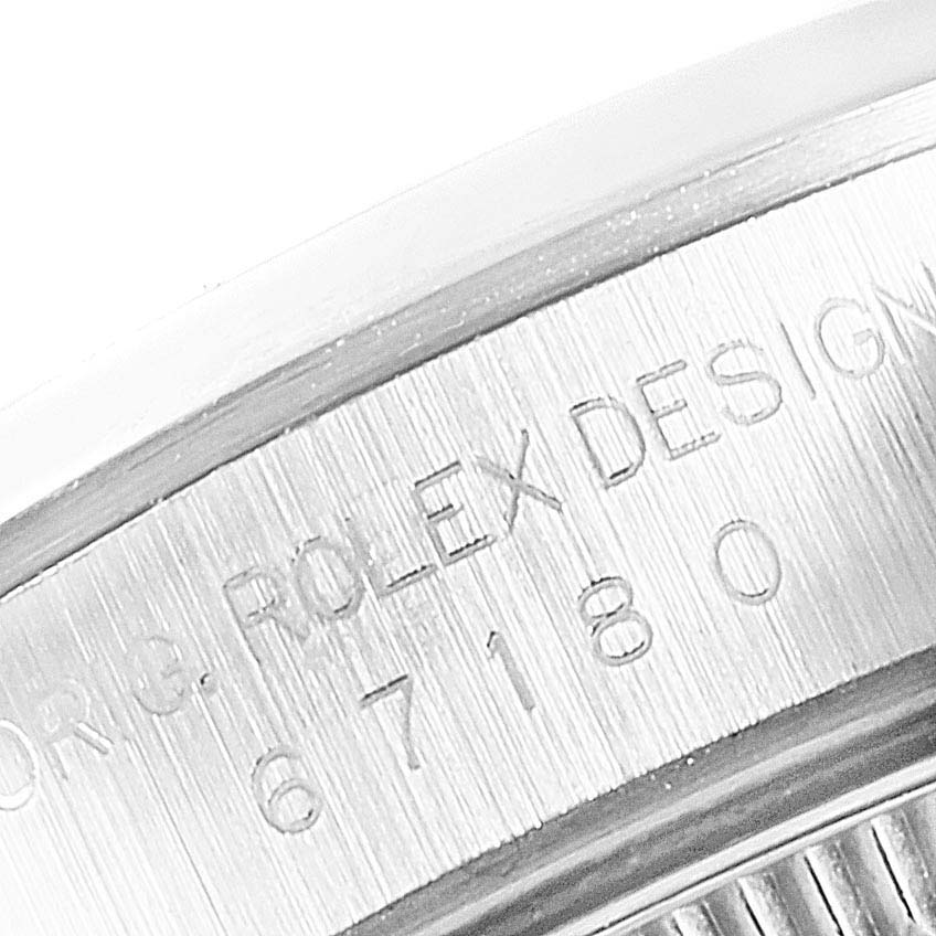 The image shows a close-up of the side of the bezel of a Rolex Oyster Perpetual 67180 Women
s Stainless Steel Black Dial 67180 Women
s Stainless Steel Black Dial watch, displaying the engraved model and design numbers.