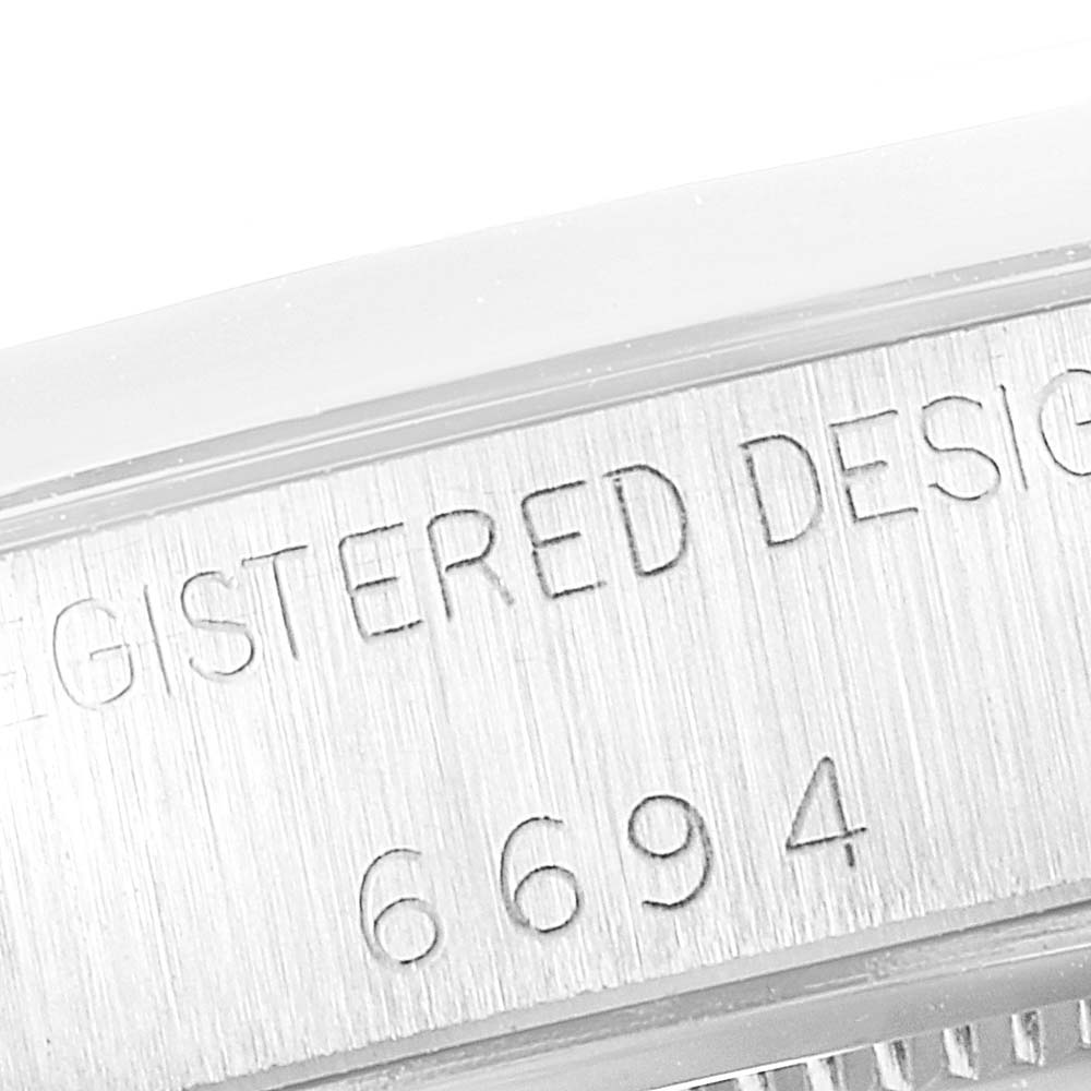 The image shows a close-up view of the case side of a Rolex Date 6694 Men's Stainless Steel Silver Dial 6694 Men's Stainless Steel Silver Dial model watch, focusing on the engraved "REGISTERED DESIGN 6694."