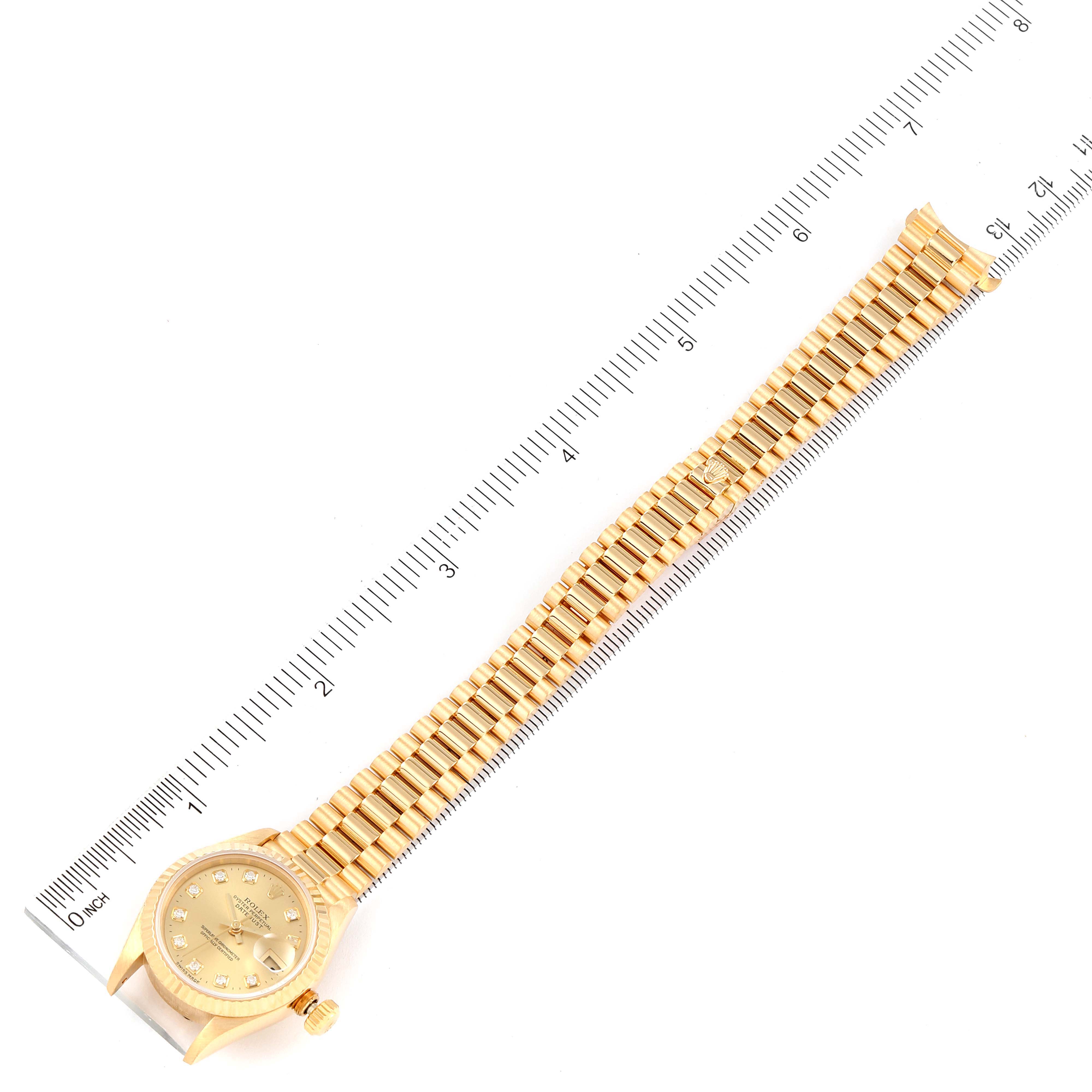 The image shows a top-down view of a Rolex President 69178 Women
s Yellow Gold Champagne Dial 69178 Women
s Yellow Gold Champagne Dial model watch, including its face, case, crown, and full bracelet laid against a ruler.