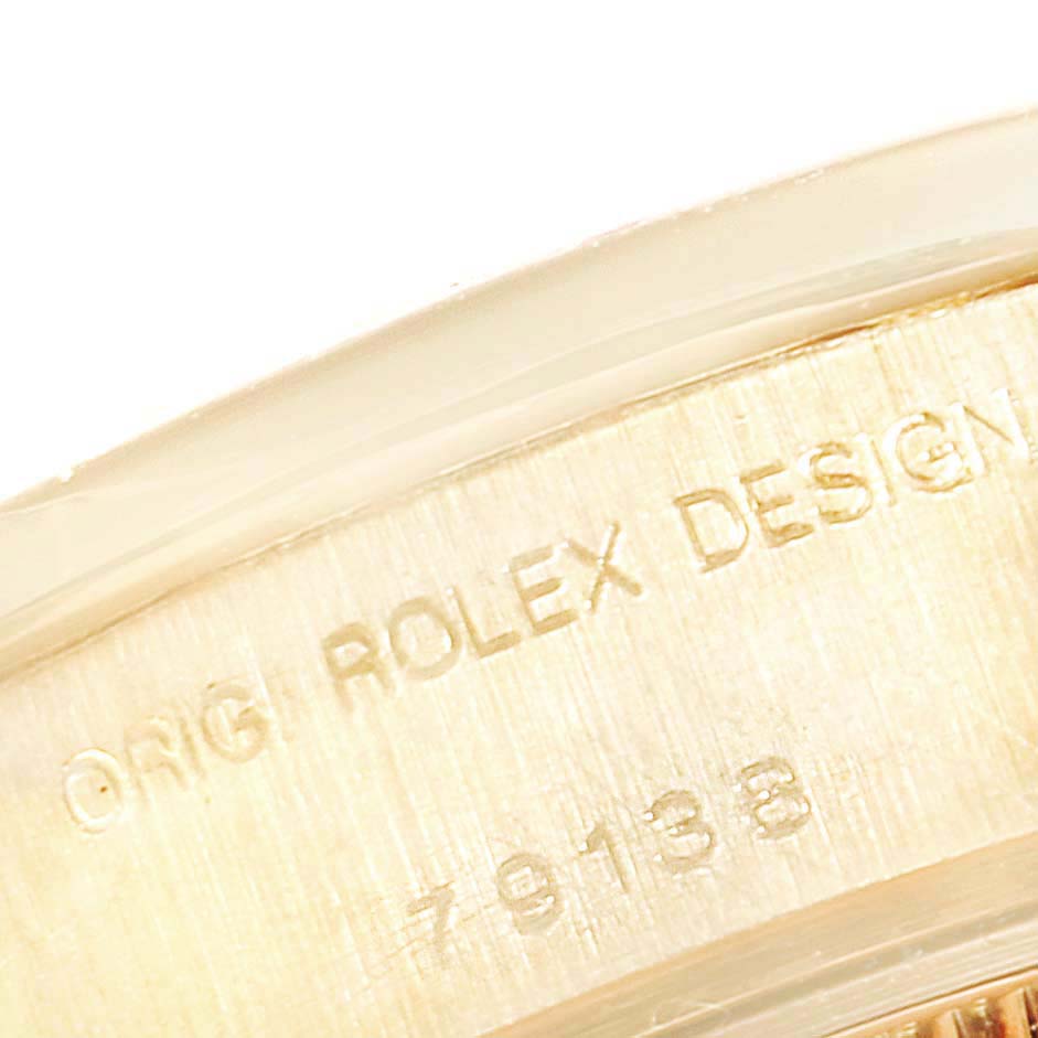 The image shows a close-up of the inner side of the bezel of a Rolex President 79138 Women
s Yellow Gold Mother of Pearl Dial 79138 Women
s Yellow Gold Mother of Pearl Dial model, featuring an engraving.