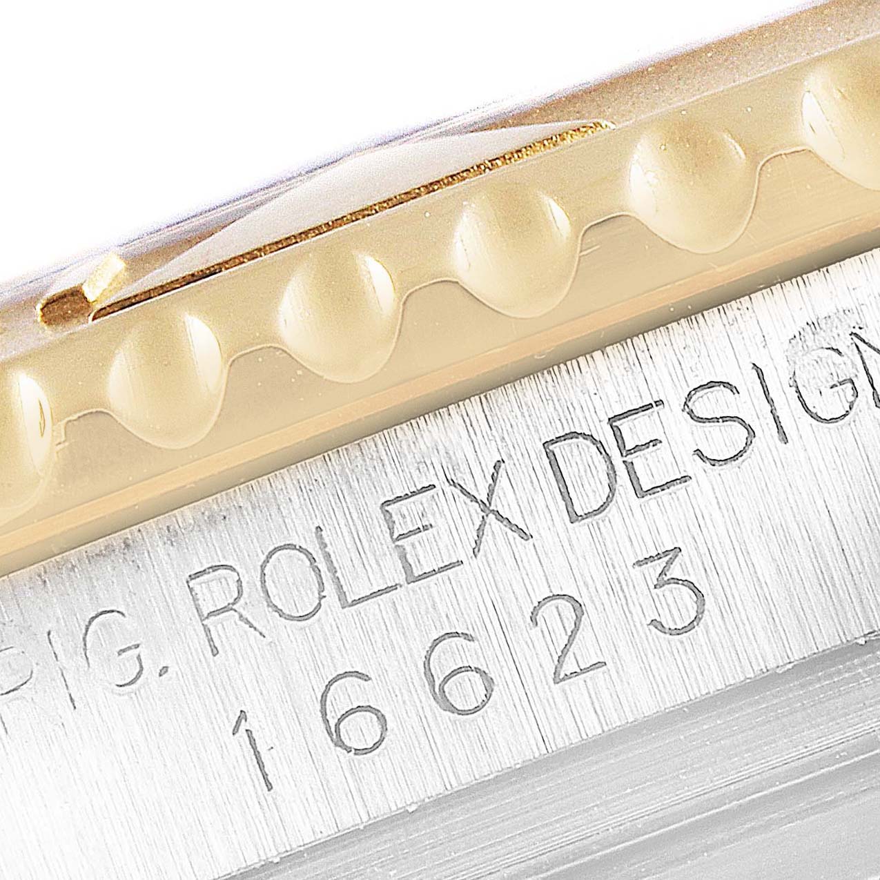 This close-up image shows the engraved model number and part of the bezel of a Rolex Yacht-Master 16623 Men
s Steel and Gold (two tone) Grey Dial 16623 Men
s Steel and Gold (two tone) Grey Dial watch.