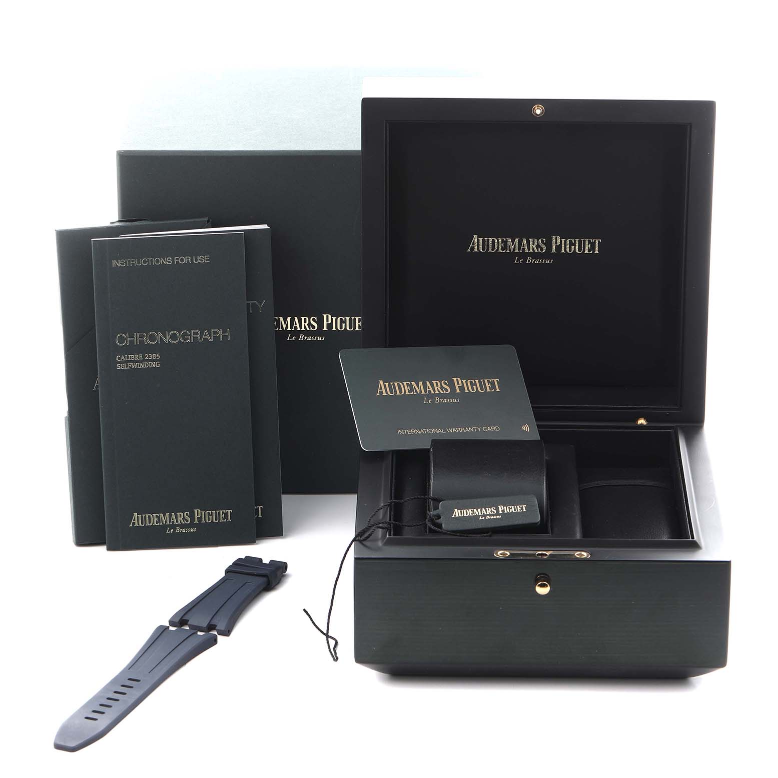 The image shows Audemars Piguet Royal Oak Offshore 26480TI.OO.A027CA.01 Men's Titanium Blue Dial 26480TI.OO.A027CA.01 Men's Titanium Blue Dial accessories, including the box, warranty card, manuals, and a strap, viewed from the front.