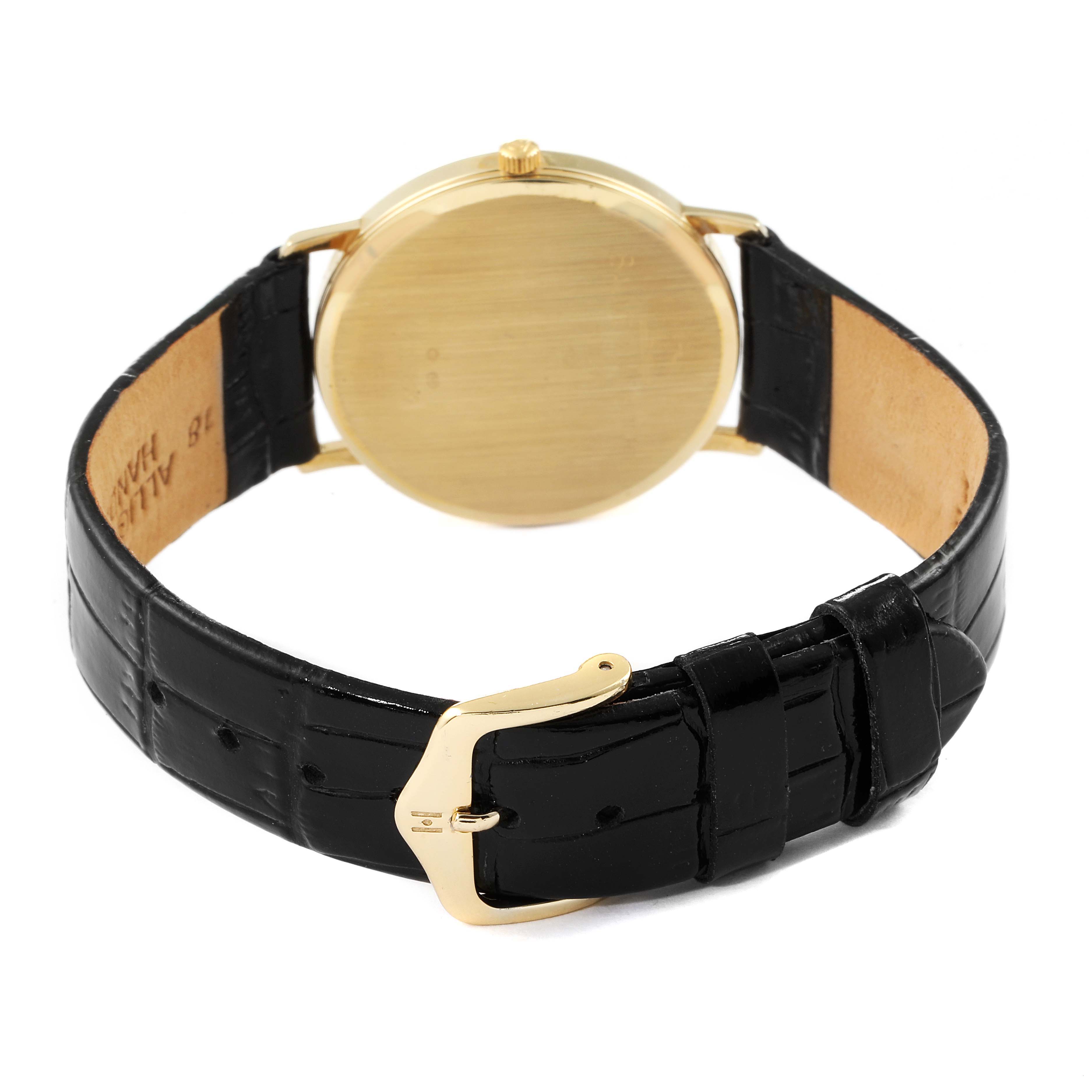 The image shows the back view of a Baume & Mercier Classima MV045093 Men's Yellow Gold White Dial MV045093 Men's Yellow Gold White Dial watch, highlighting its gold case and black leather strap with buckle.