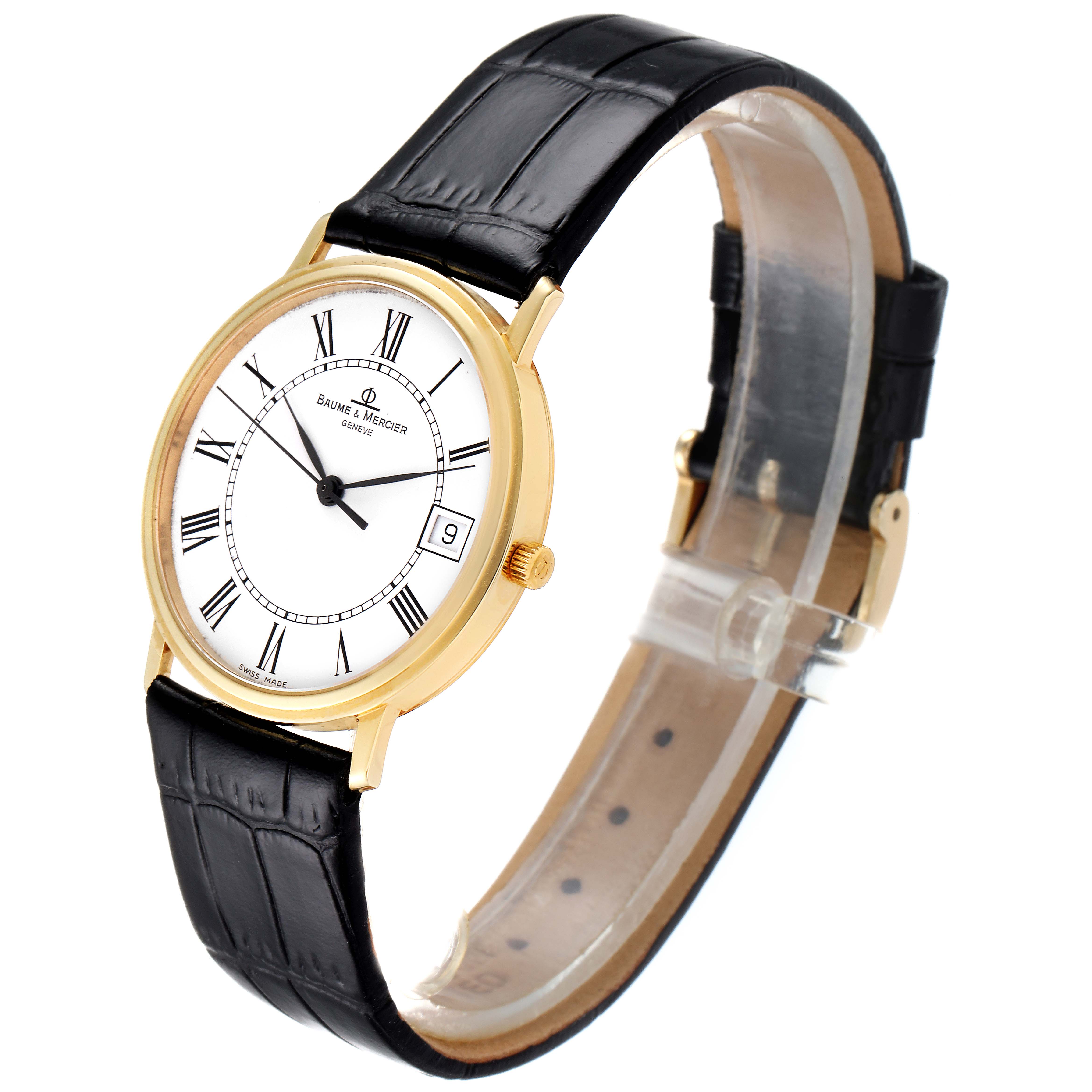 The Baume & Mercier Classima MV045093 Men's Yellow Gold White Dial MV045093 Men's Yellow Gold White Dial watch is shown at a slight angle, displaying its gold case, white dial with Roman numerals, date window, and black leather strap.