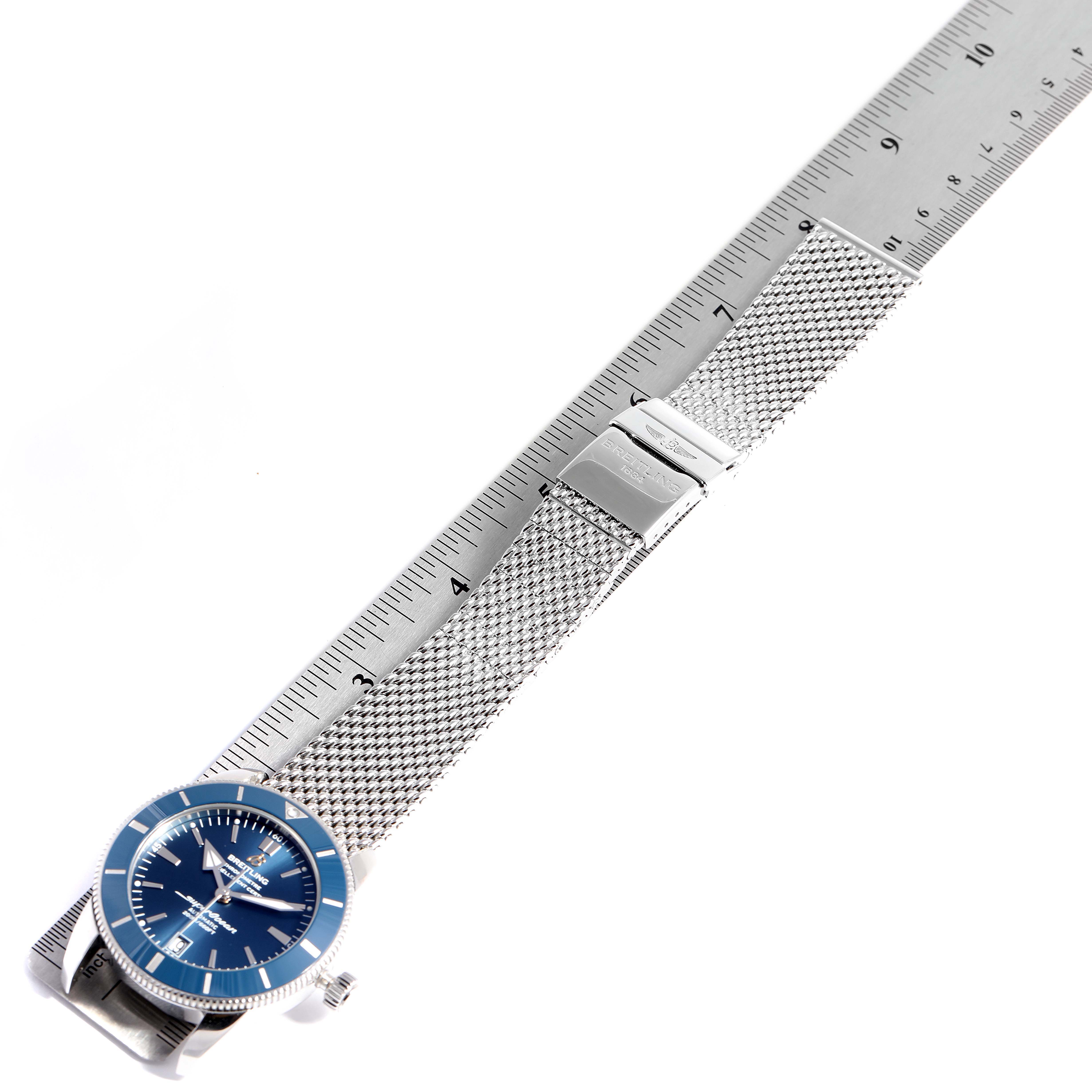 The image shows a Breitling Superocean AB2010161C1A1 Men's Stainless Steel Blue Dial AB2010161C1A1 Men's Stainless Steel Blue Dial watch flat, aligned with a ruler, highlighting its face, bezel, and mesh bracelet.