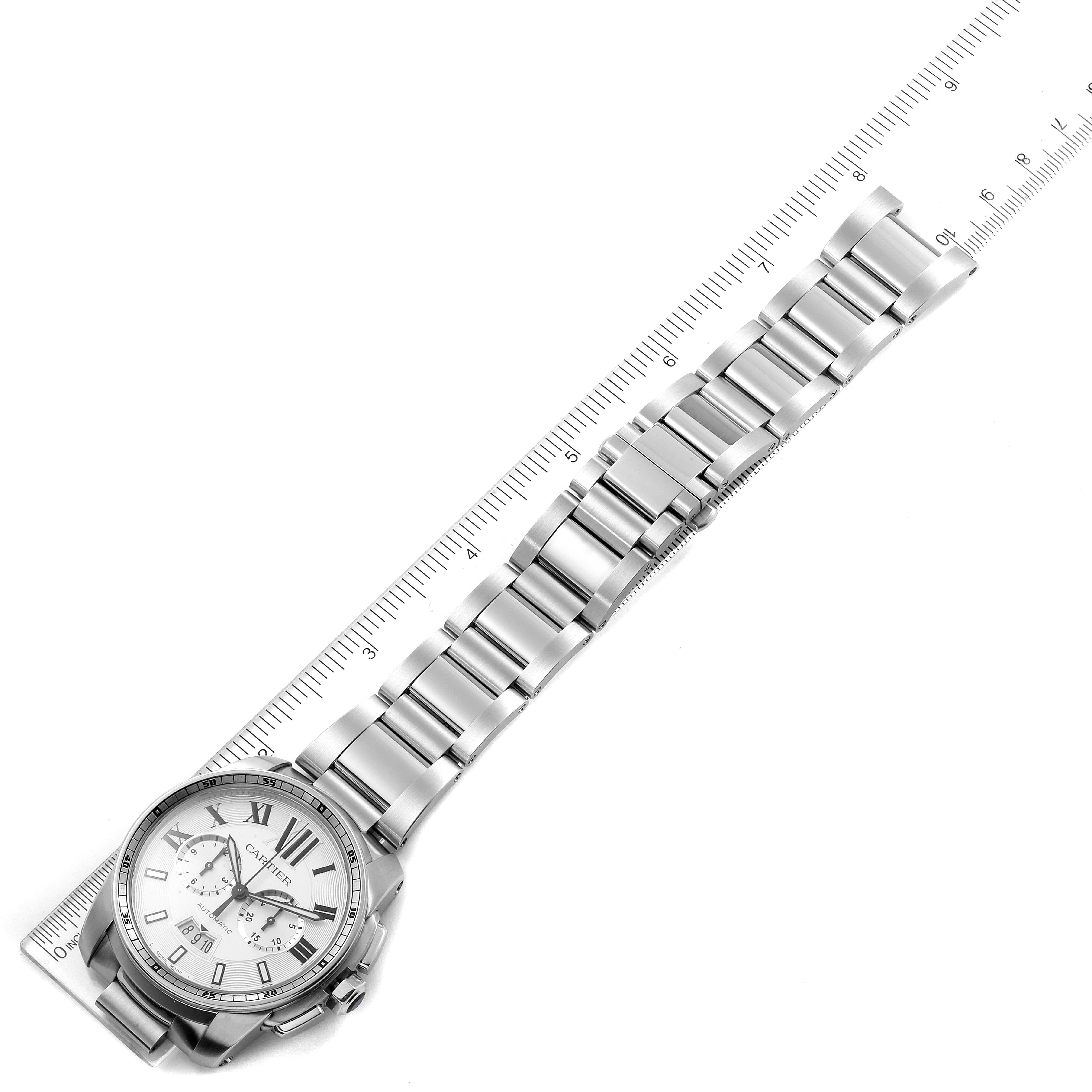 The image shows a Calibre de Cartier watch by Cartier, laid flat with the bracelet extended and a ruler for scale.