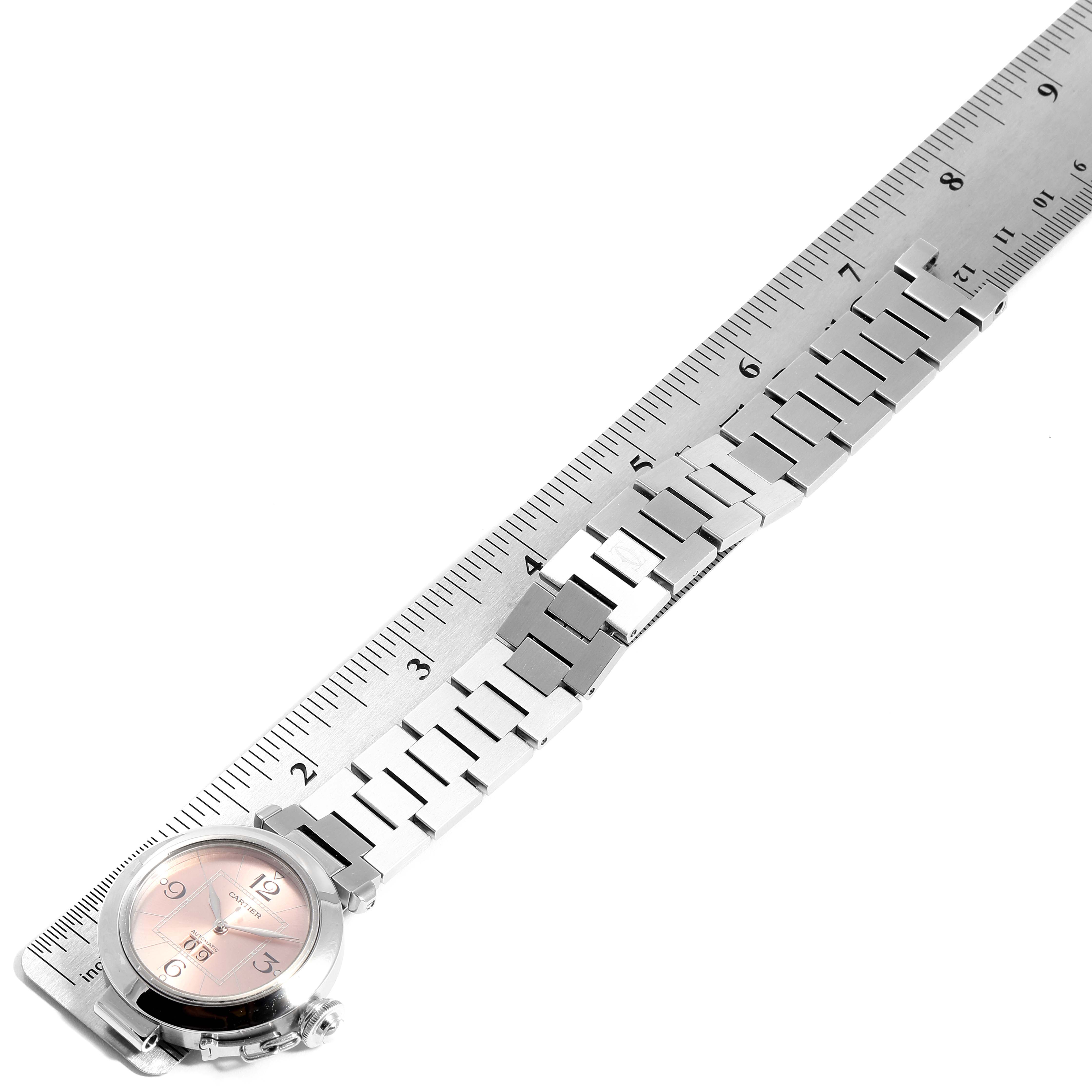 The image shows a Cartier Pasha W31058M7 Women
s Stainless Steel Pink Dial W31058M7 Women
s Stainless Steel Pink Dial watch laid next to a ruler, displaying the bracelet and face from a top-down angle.