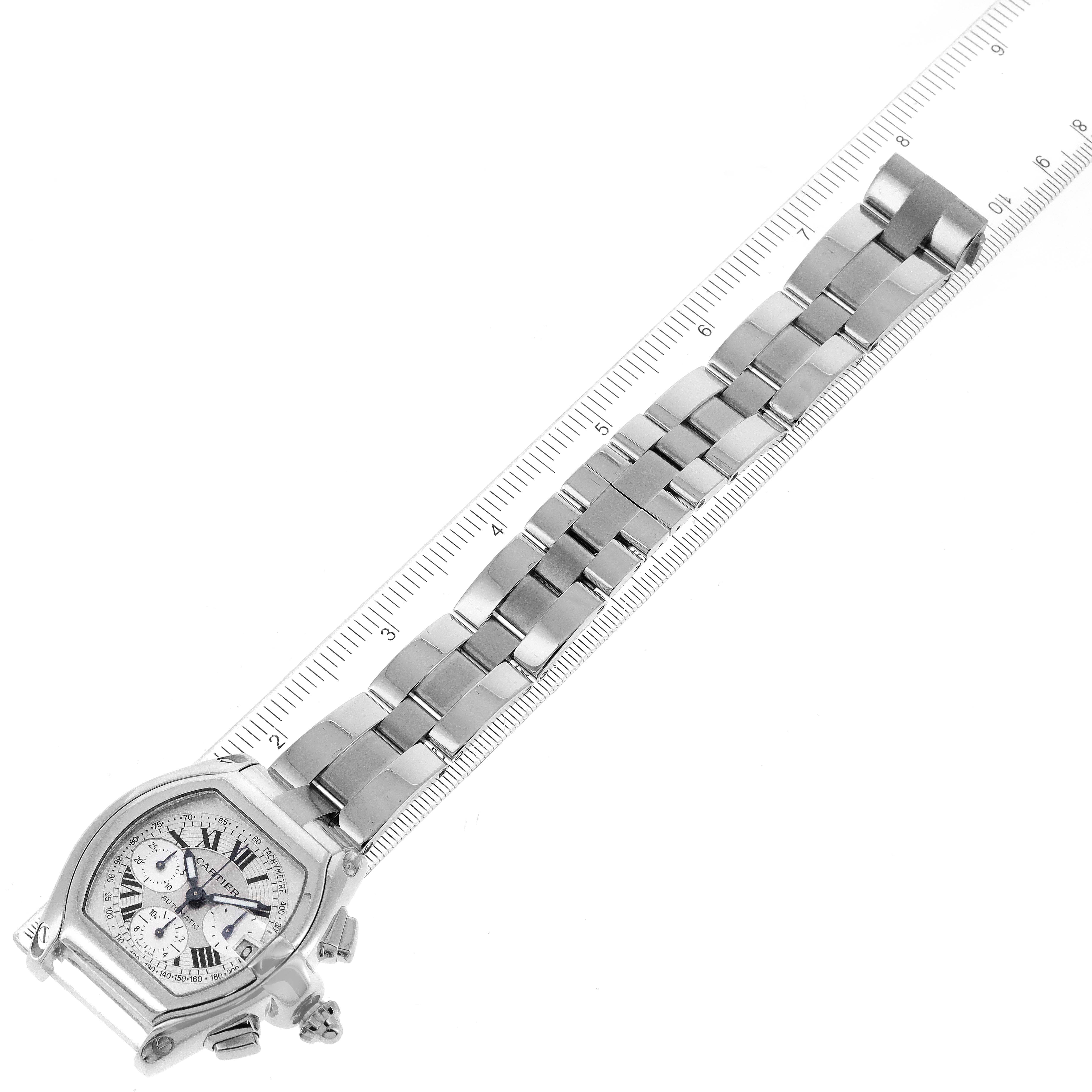The Cartier Roadster W62006X6 Men's Stainless Steel Silver Dial W62006X6 Men's Stainless Steel Silver Dial watch is shown at an angle, with its face, bracelet, and adjacent ruler for measurement.