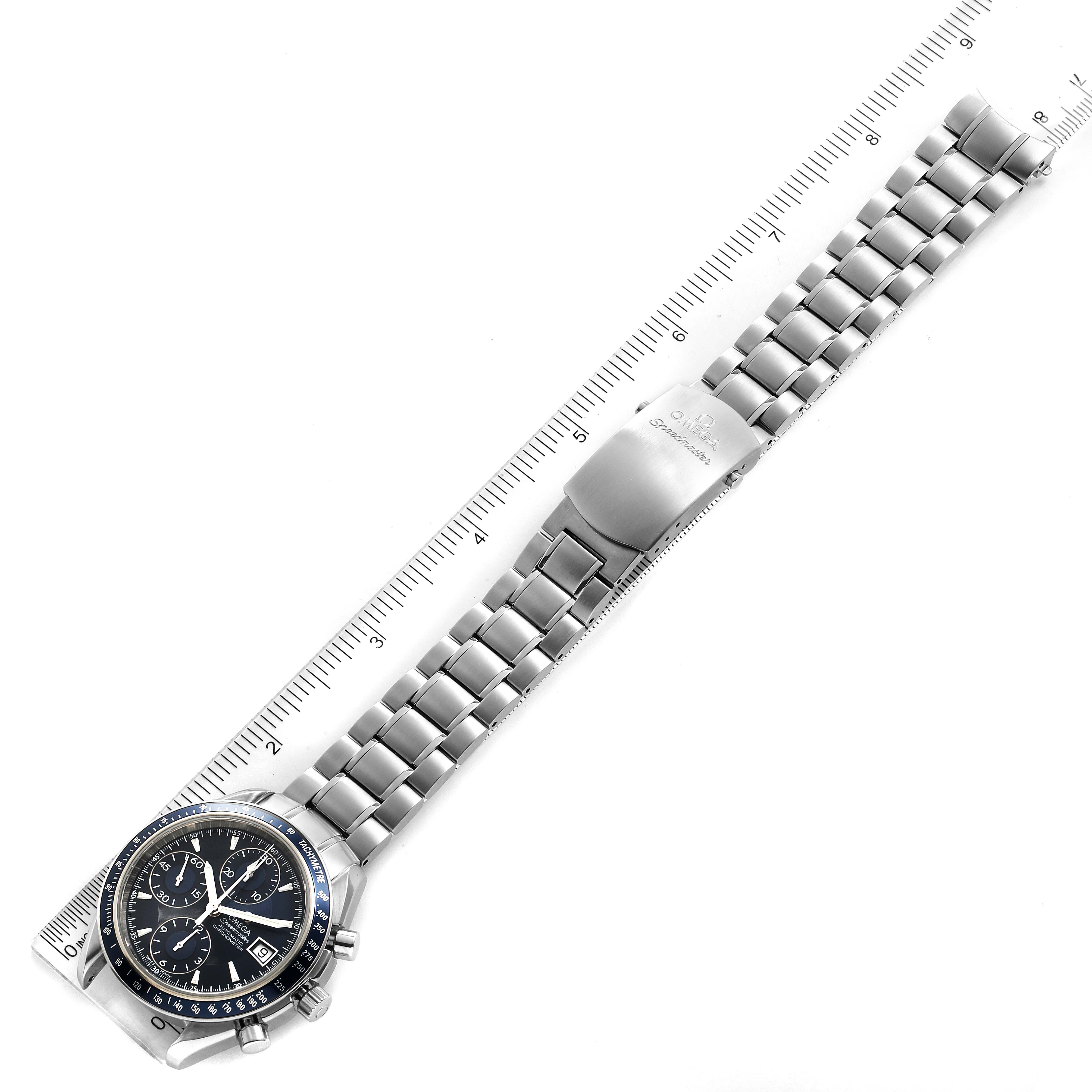 The image shows an Omega Speedmaster 3212.80.00 Men
s Stainless Steel Blue Dial 3212.80.00 Men
s Stainless Steel Blue Dial watch angled diagonally with its full stainless steel bracelet and clasp displayed against a ruler.