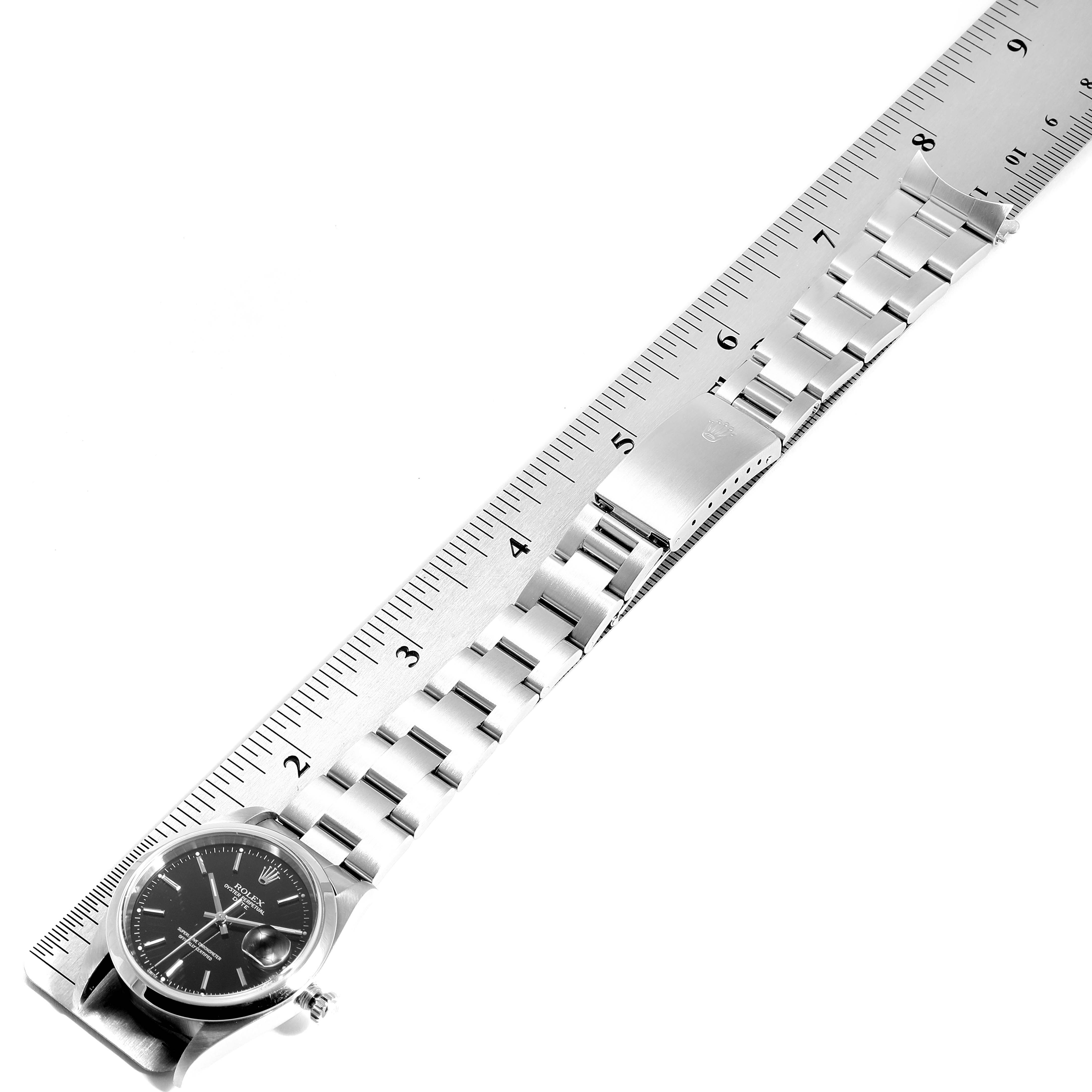 The image shows a Rolex Date 15200 Men's Stainless Steel Black Dial 15200 Men's Stainless Steel Black Dial model watch lying flat next to a ruler, displaying the face, bracelet, and clasp.