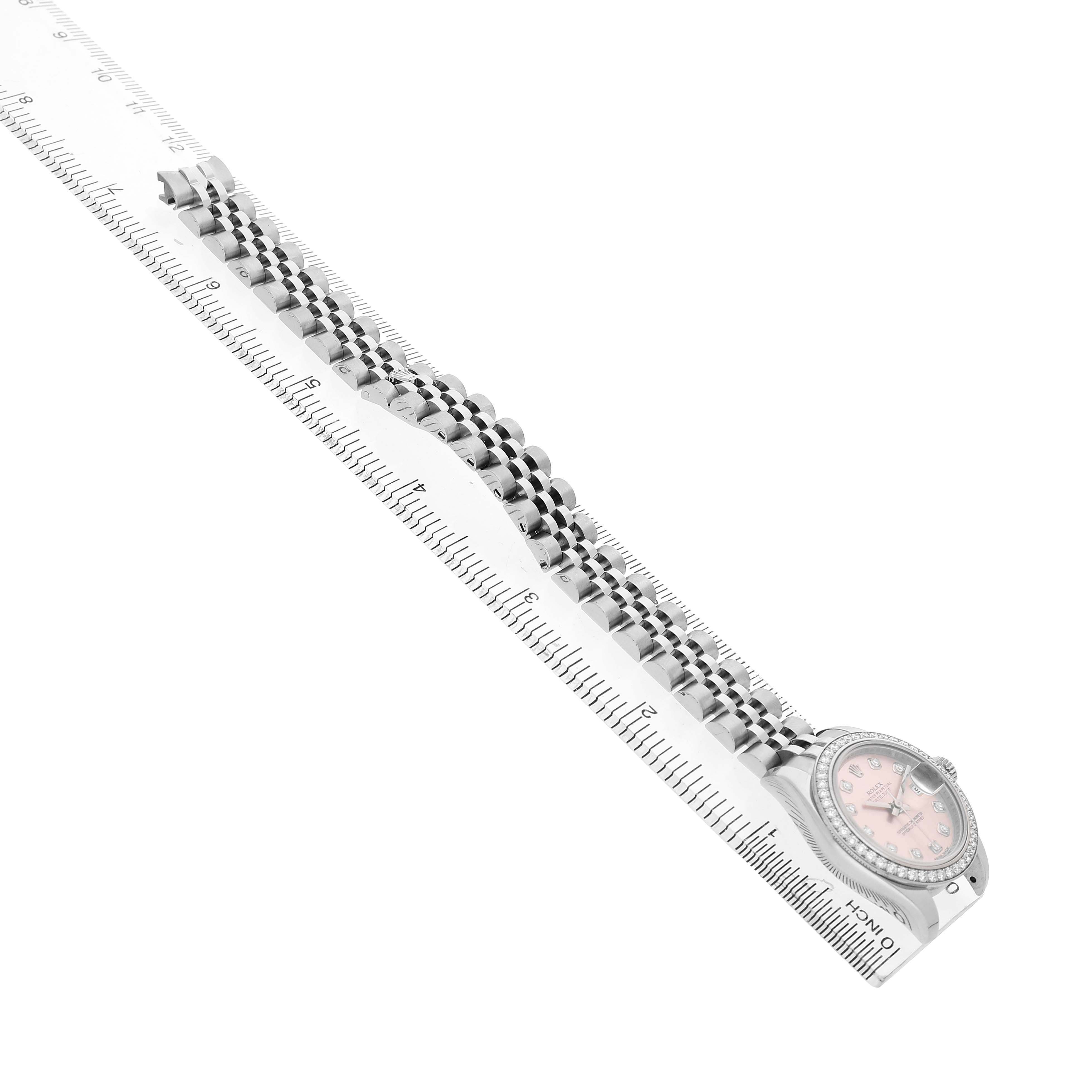 The Rolex Datejust 179384 Women's Stainless Steel Pink Dial watch is shown at an angle displaying its bracelet, case, and dial alongside a ruler for size comparison.