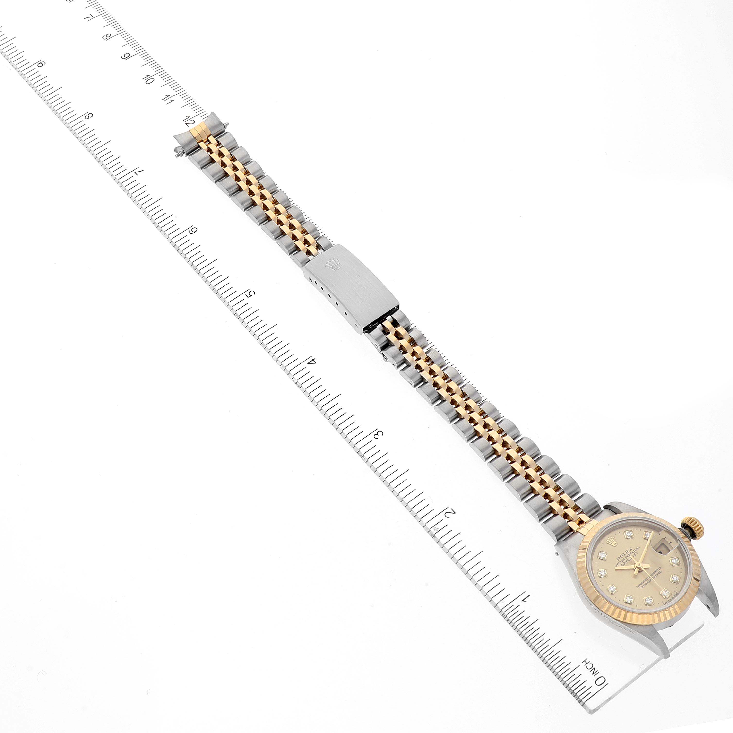 The image shows a Rolex Datejust 69173 Women
s Steel and Gold (two tone) Champagne Dial 69173 Women
s Steel and Gold (two tone) Champagne Dial watch lying flat with its bracelet extended alongside a ruler for scale.