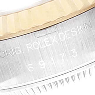 The image shows a close-up of the side of a Rolex Datejust 69173 Women
s Steel and Gold (two tone) Champagne Dial 69173 Women
s Steel and Gold (two tone) Champagne Dial, displaying the Rolex design engraving and the model number 69173.