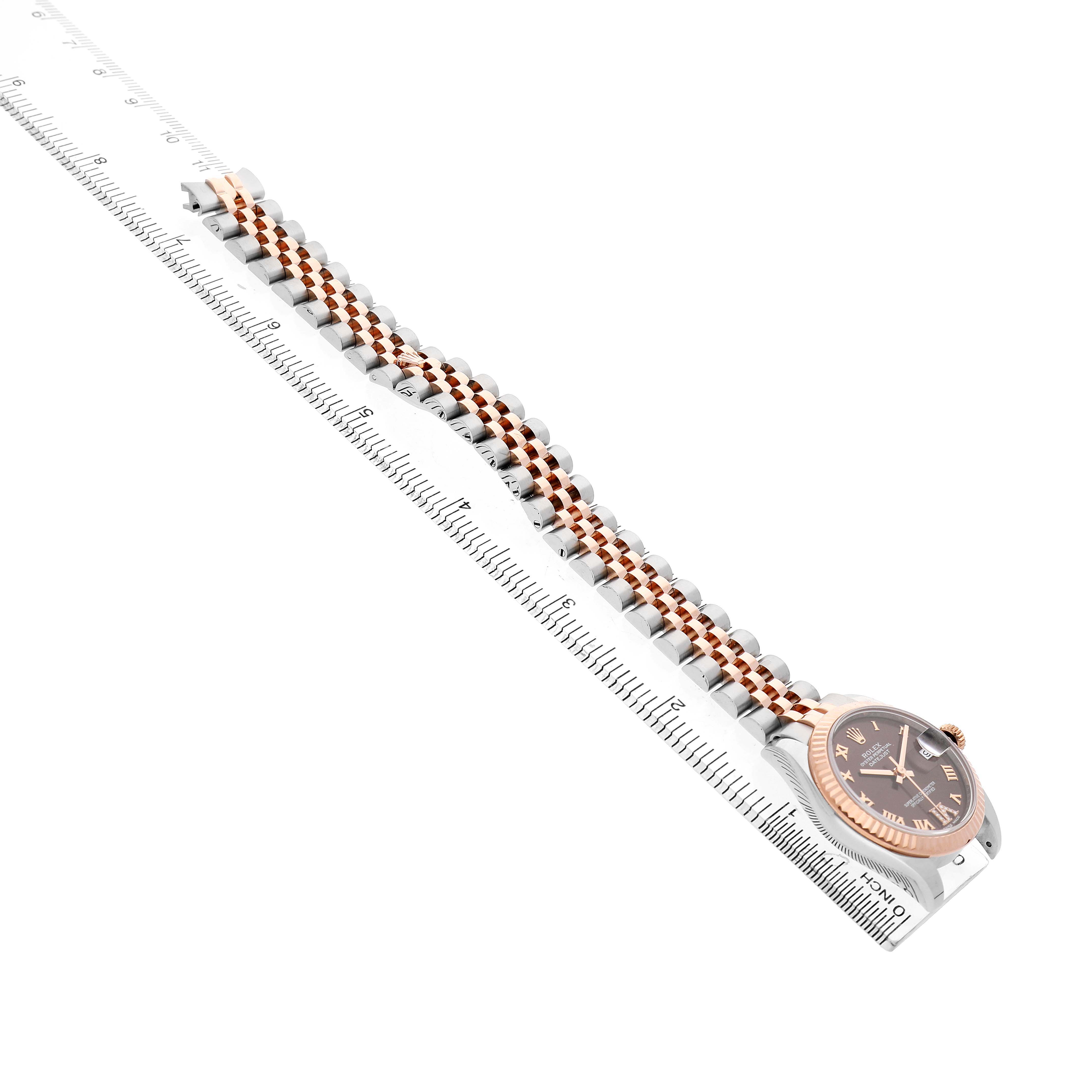 The Rolex Mid-Size 178271 Women's Stainless Steel Brown Dial watch is shown at an angle highlighting the face, bezel, and bracelet against a ruler.
