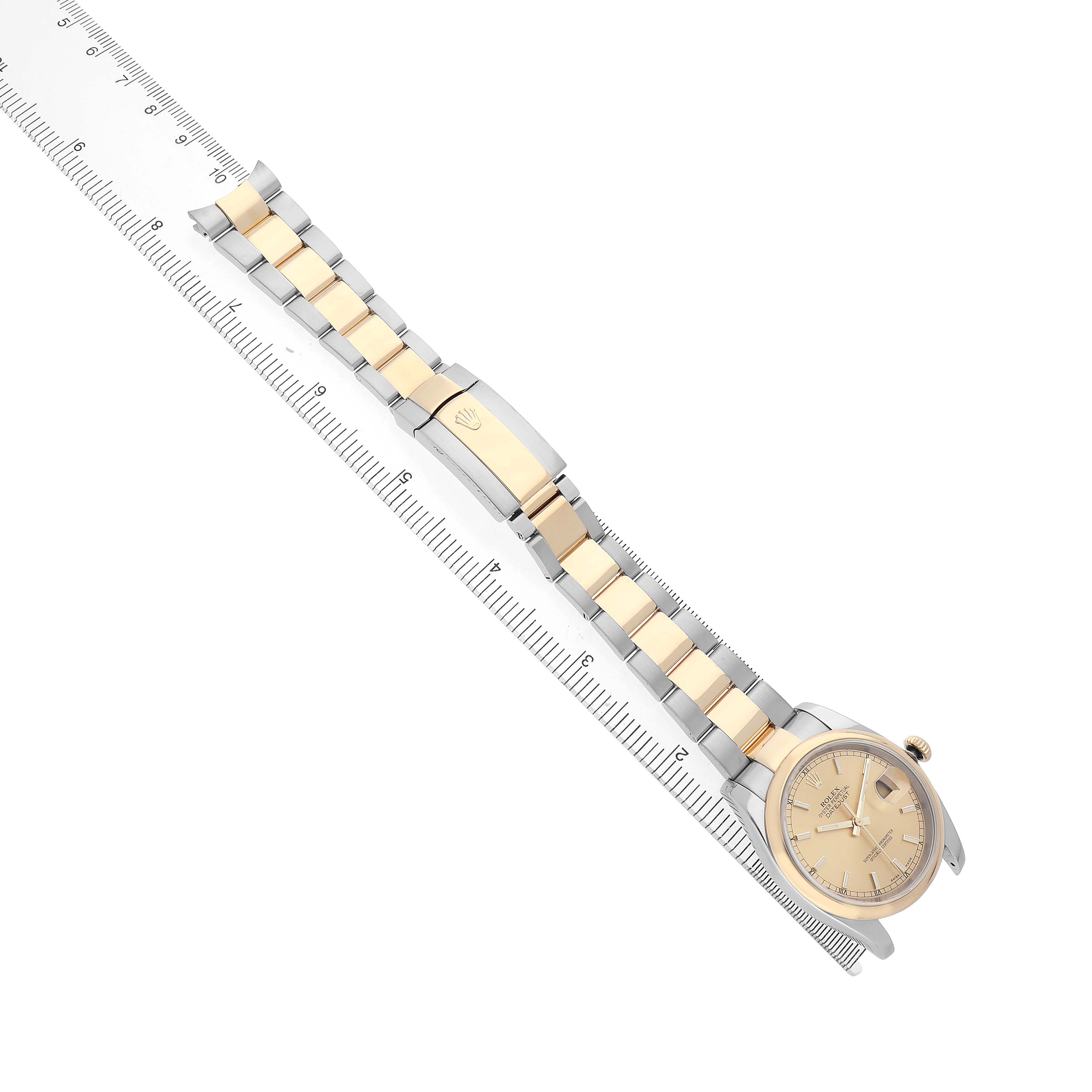 The Rolex Datejust 116233 Men's Stainless Steel Champagne Dial watch is angled diagonally with a full view of the bracelet alongside a ruler.