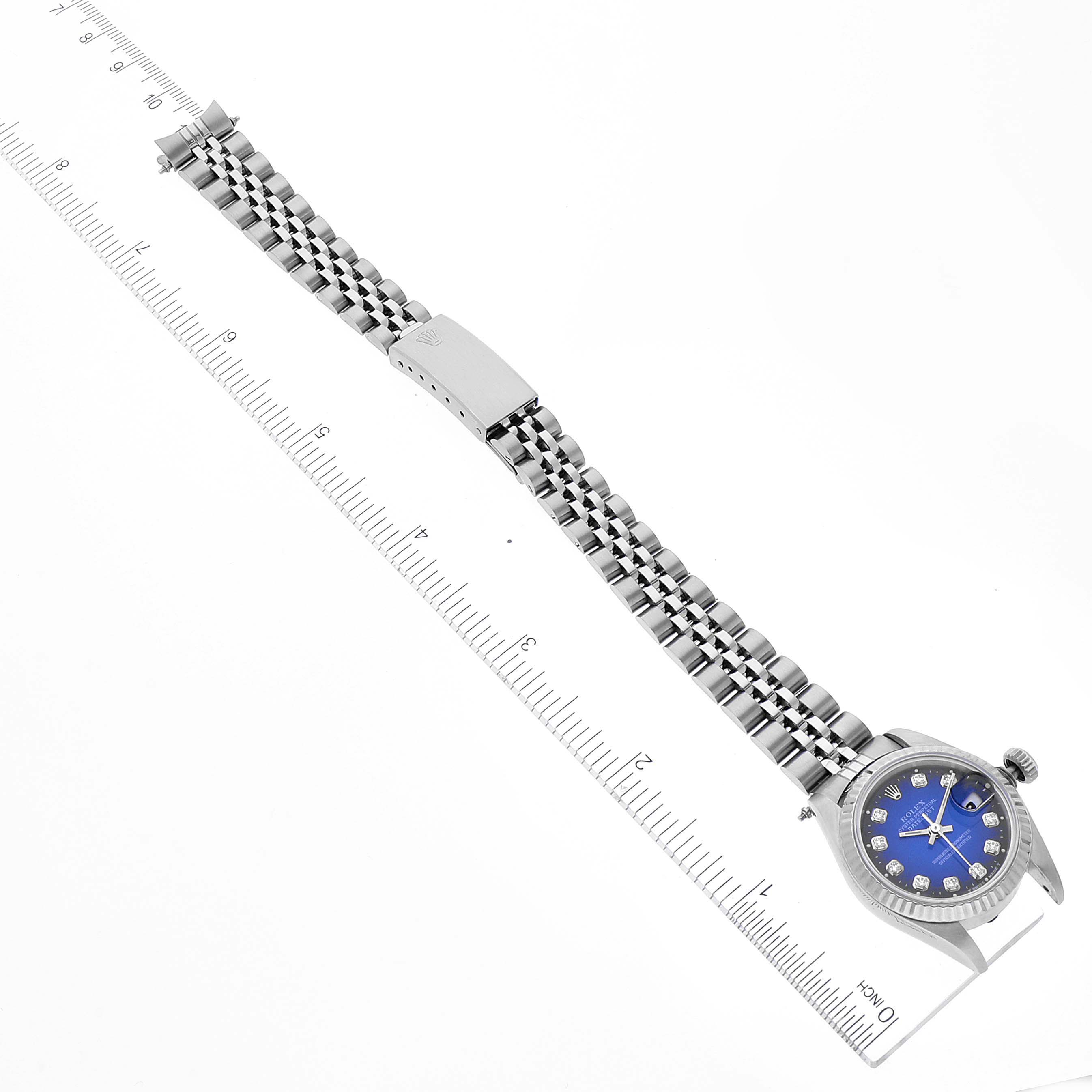 This image shows a full-length view of a Rolex Datejust 69174 Women
s Stainless Steel Blue Dial 69174 Women
s Stainless Steel Blue Dial watch with a blue face and metal bracelet, measured alongside a ruler.