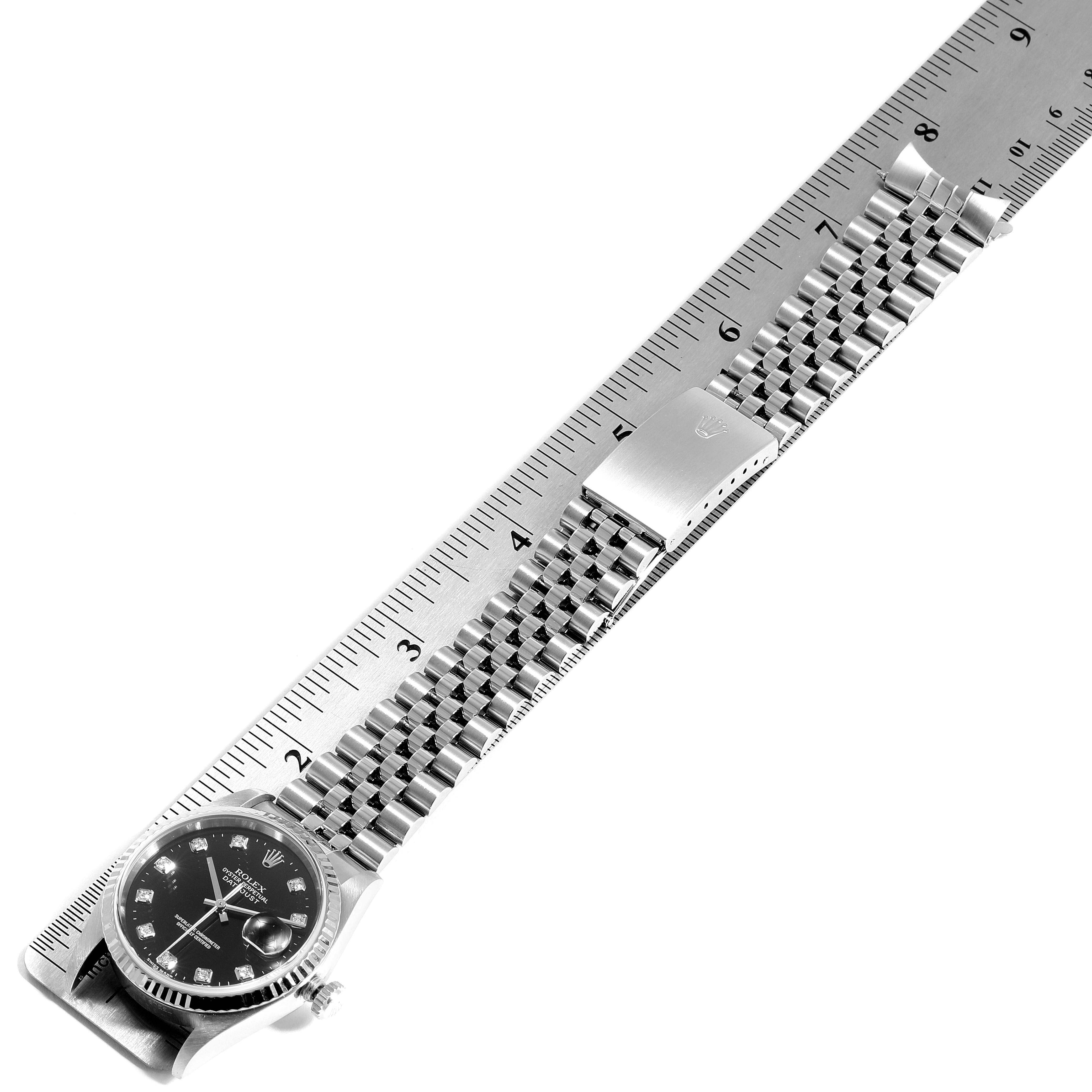 The Rolex Datejust 16234 Men
s Stainless Steel Black Dial 16234 Men
s Stainless Steel Black Dial watch is shown from a top-down angle, displaying its face, bracelet, and clasp against a measuring ruler.