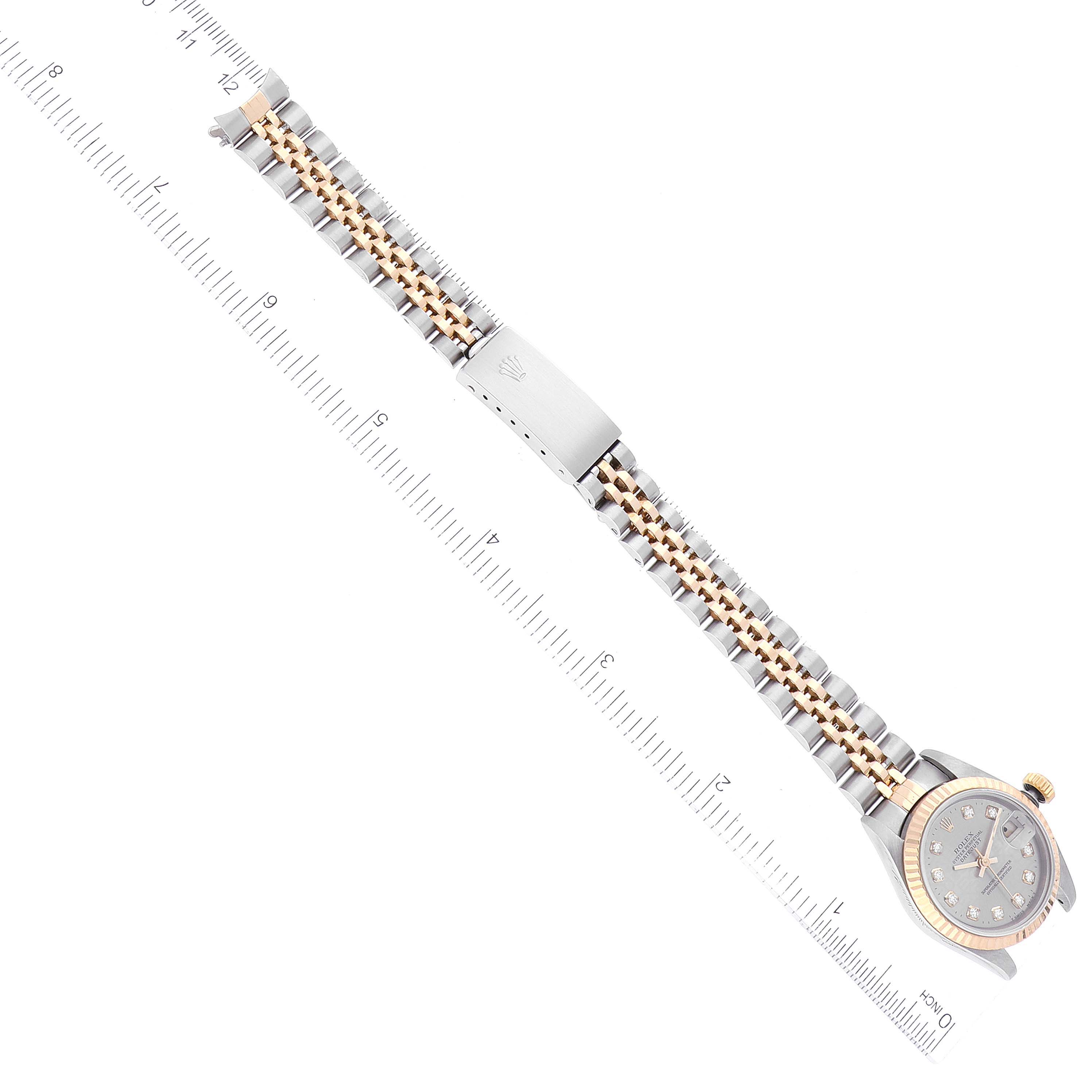 The image shows an overhead view of a Rolex Datejust 69173 Women's Steel and Gold (two tone) Grey Dial 69173 Women's Steel and Gold (two tone) Grey Dial watch with its two-tone metal bracelet and clasp, alongside a ruler for scale.