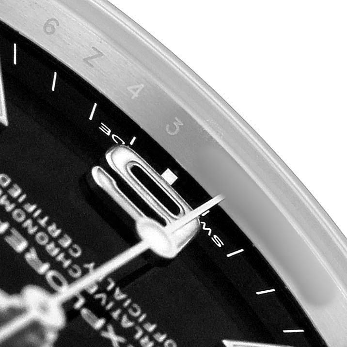 The image shows a close-up of the Explorer model by Rolex, focusing on the hands, markers, and part of the dial edge.