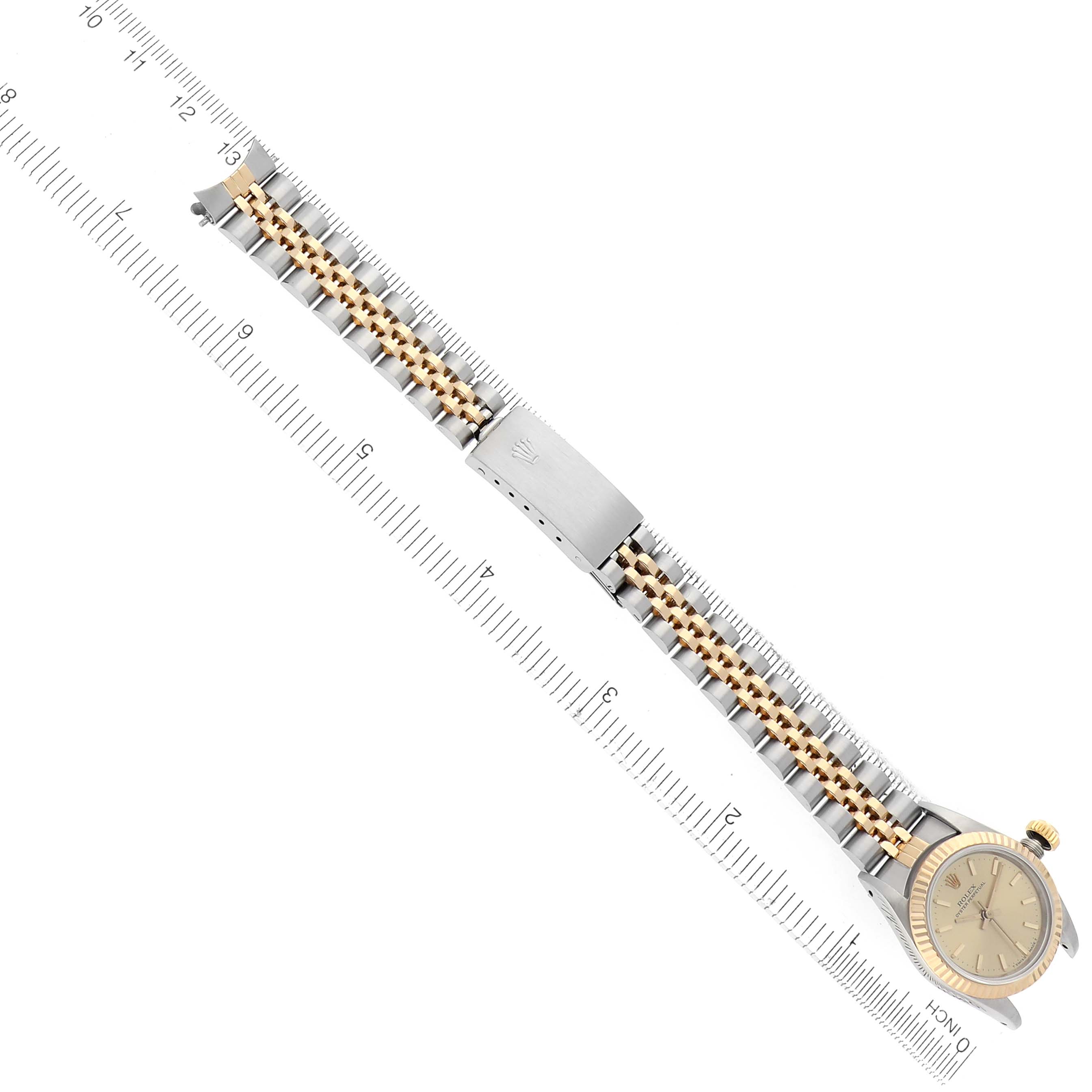 The image shows a Rolex Oyster Perpetual 67193 Women's Steel and Gold (two tone) Champagne Dial 67193 Women's Steel and Gold (two tone) Champagne Dial watch laid flat beside a ruler, highlighting the bracelet and clasp details.
