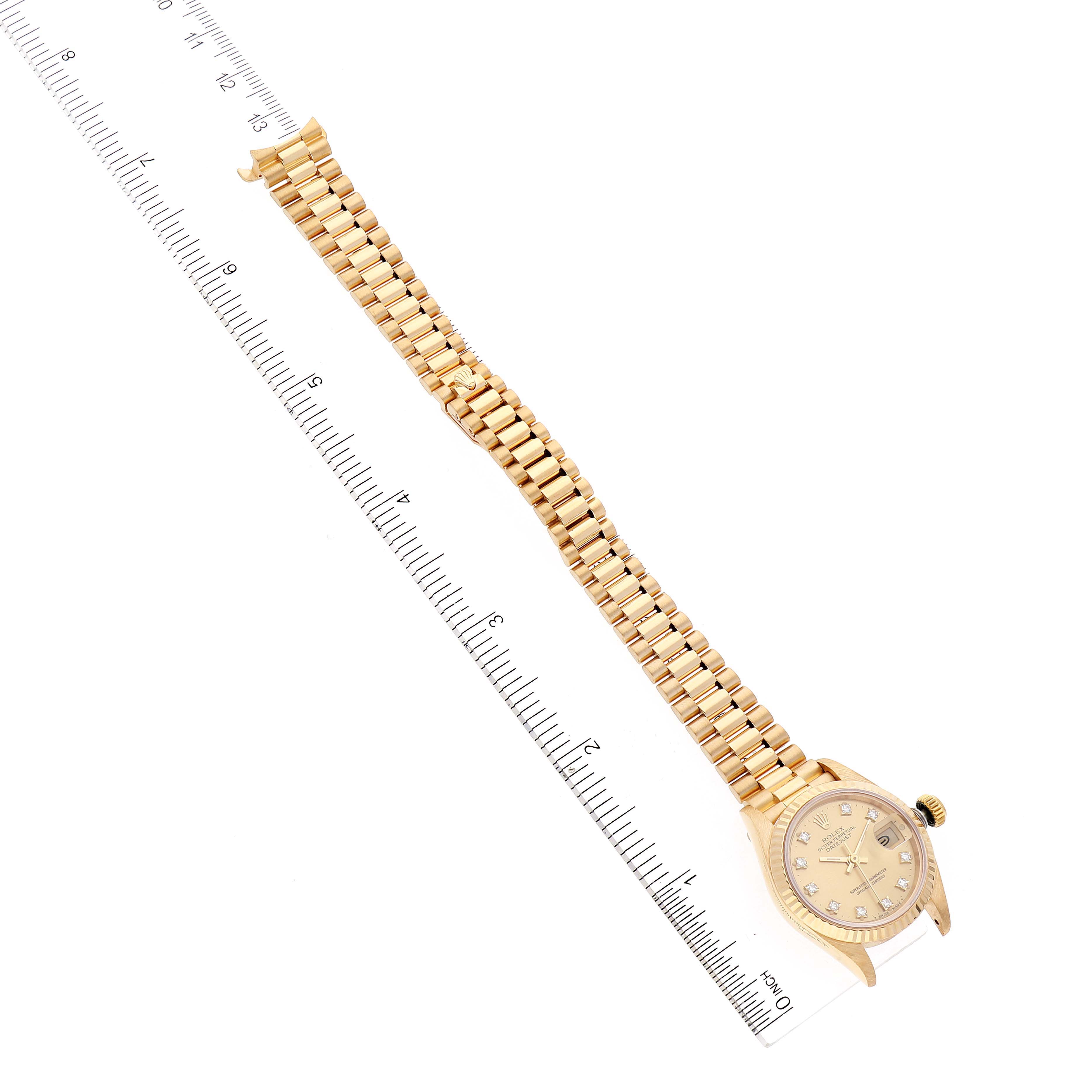 The image shows a President model Rolex watch placed next to a ruler, displaying its dial, band, and part of the crown.