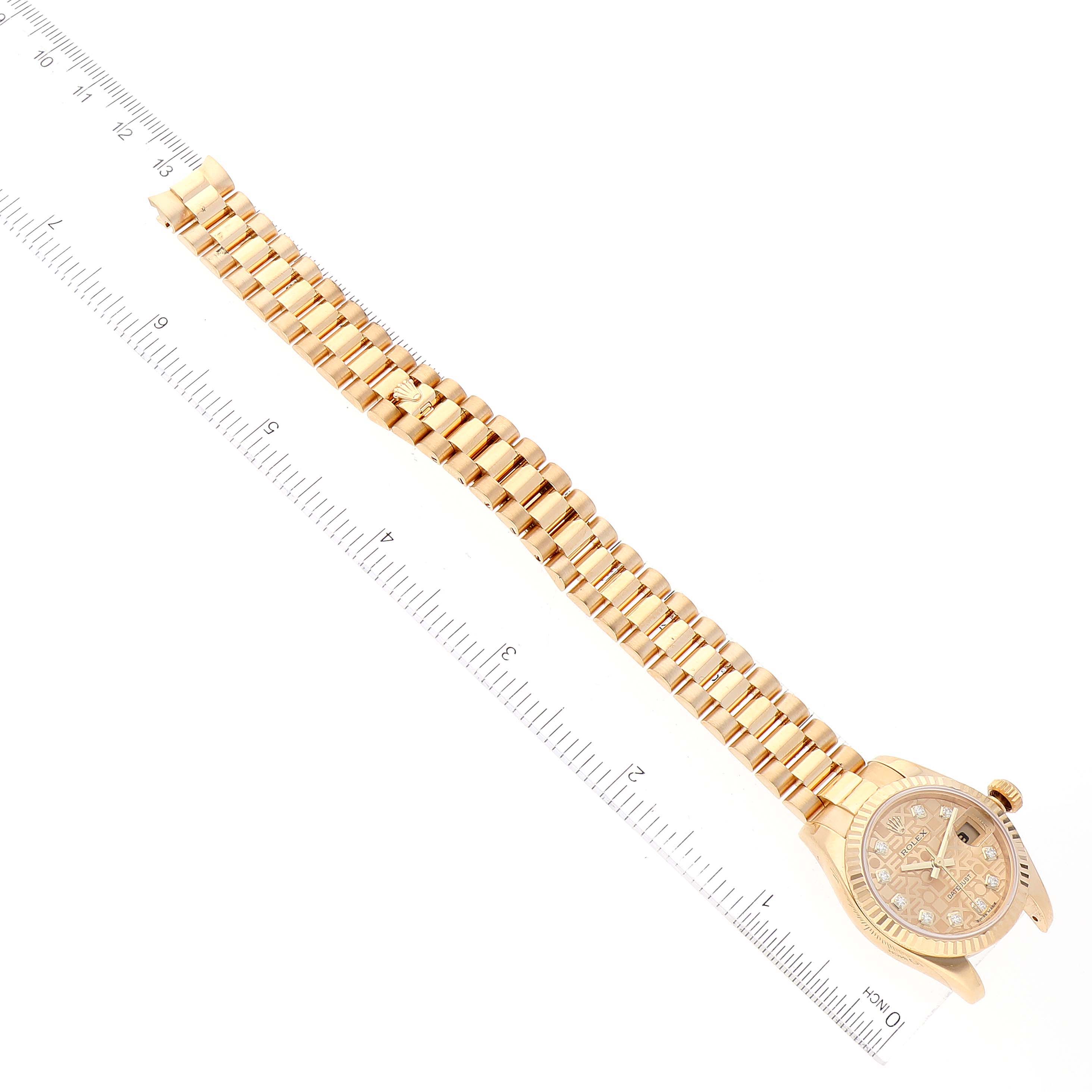 The image shows a top-down view of a Rolex President 179178 Women's Yellow Gold Champagne Dial 179178 Women's Yellow Gold Champagne Dial model watch, displaying its face and full gold bracelet near a ruler.
