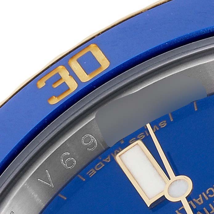 This close-up image of a Rolex Submariner 116613 Men's Steel and Gold (two tone) Blue Dial 116613 Men's Steel and Gold (two tone) Blue Dial shows a portion of the blue bezel with gold markers and part of the dial with the minute hand.