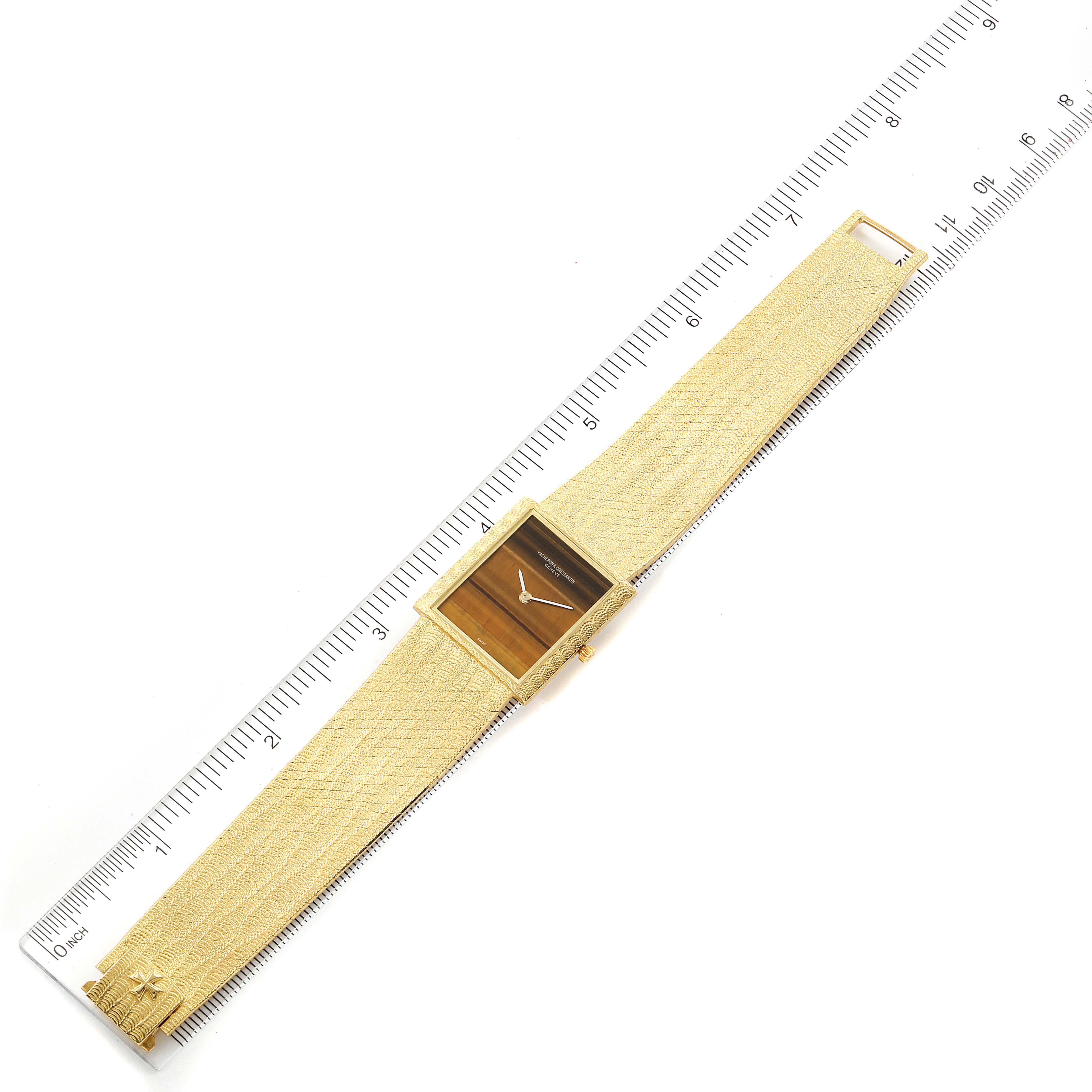 This Vacheron Constantin Vintage 7255P Men's Yellow Gold Brown Dial 7255P Men's Yellow Gold Brown Dial watch is shown from a top-down angle, highlighting its rectangular dial and textured band alongside a ruler.