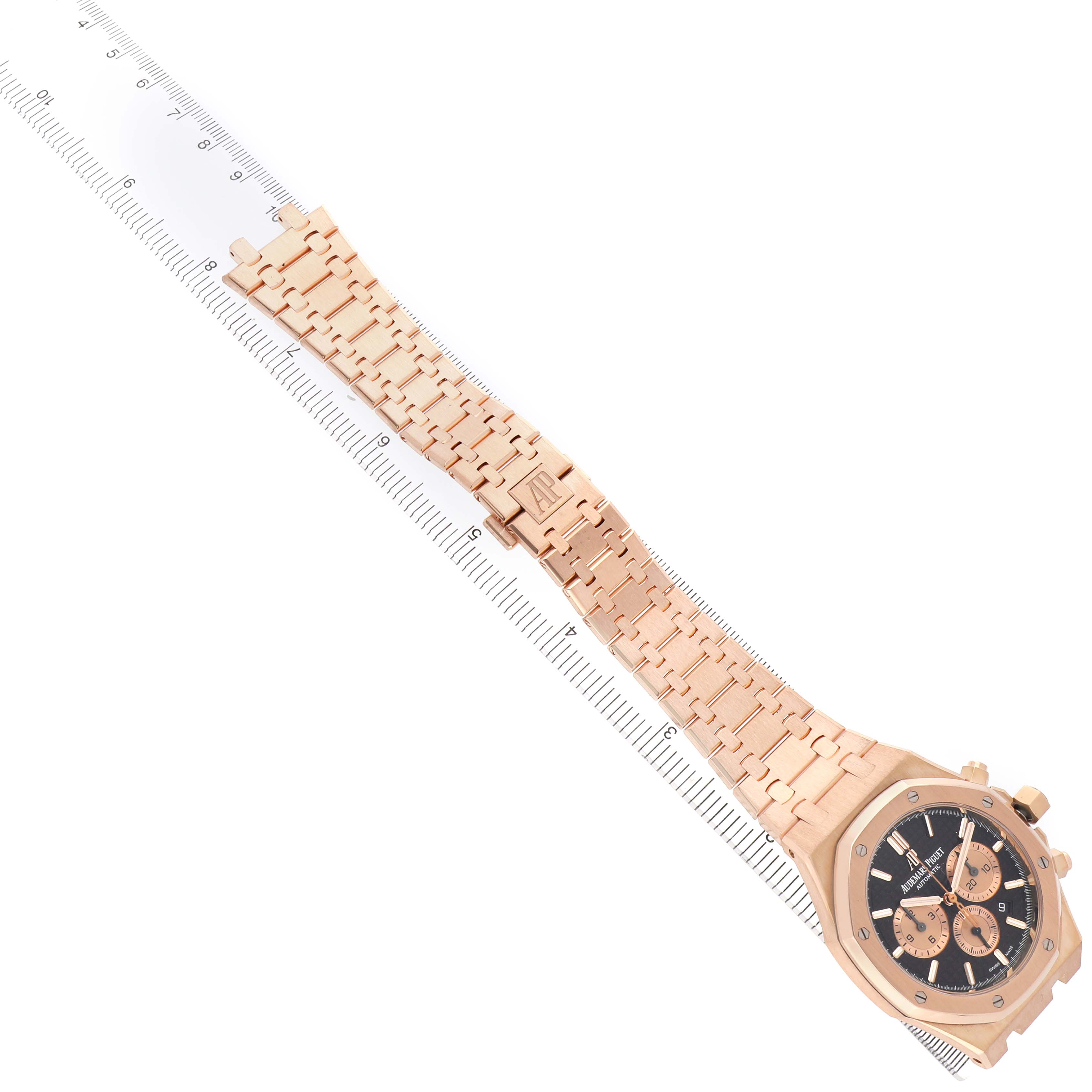 The Audemars Piguet Royal Oak 26331OR Men's Rose Gold Brown Dial is shown flat from the front, displaying the bracelet, clasp, and face diagonally across a ruler.