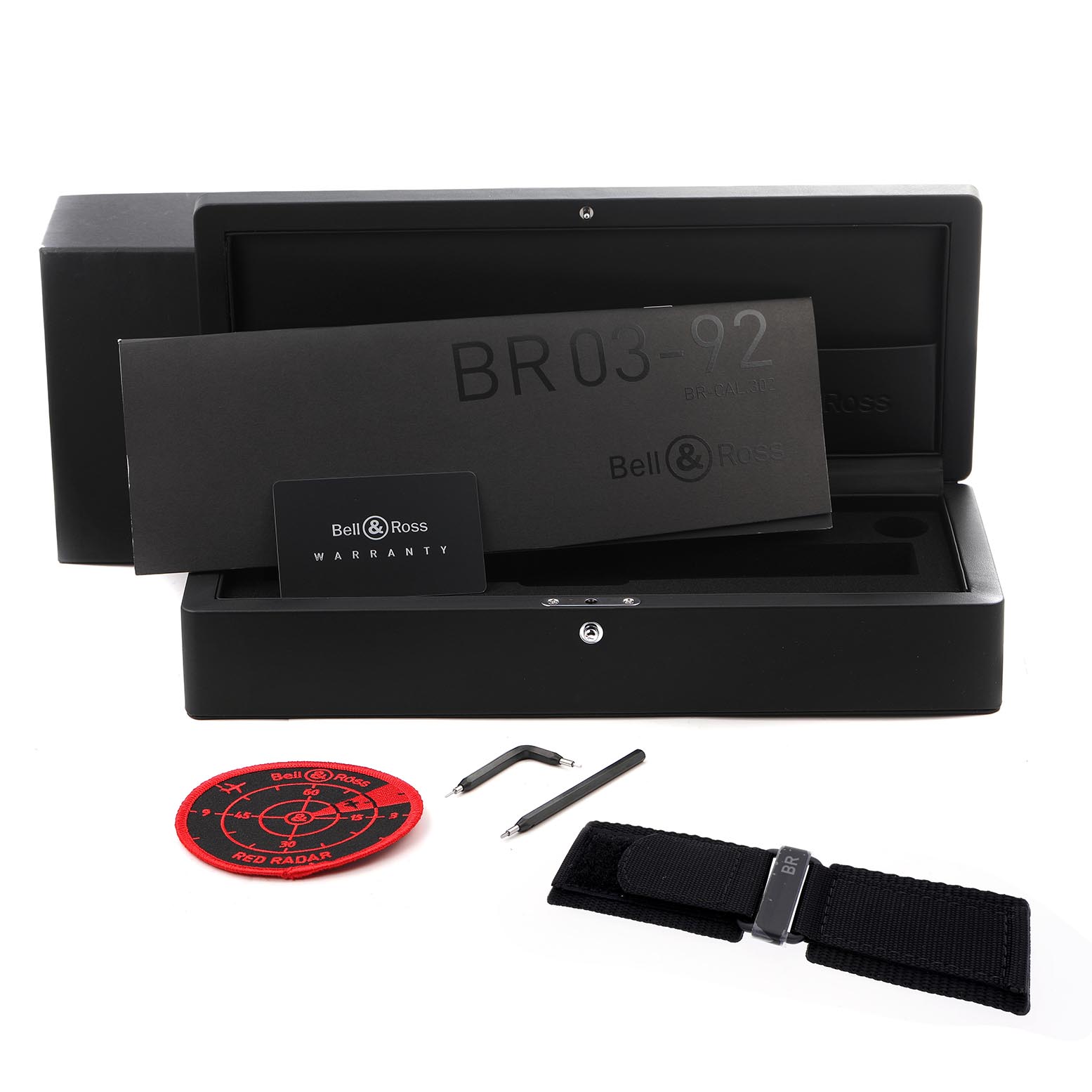 The image shows the Bell 
Ross Instruments BR0392-RRDR-CE/SRB Men
s Ceramic Black Dial BR0392-RRDR-CE/SRB Men
s Ceramic Black Dial model packaging, warranty card, additional strap, tools, and a patch.