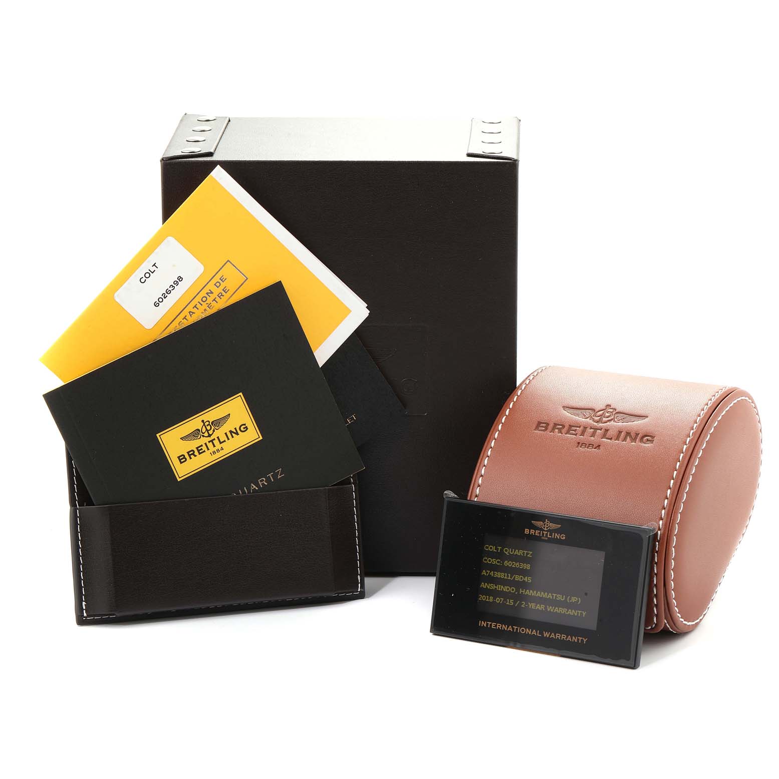 The image shows accessories for the Colt model by Breitling including the box, documentation, warranty card, and a leather case.