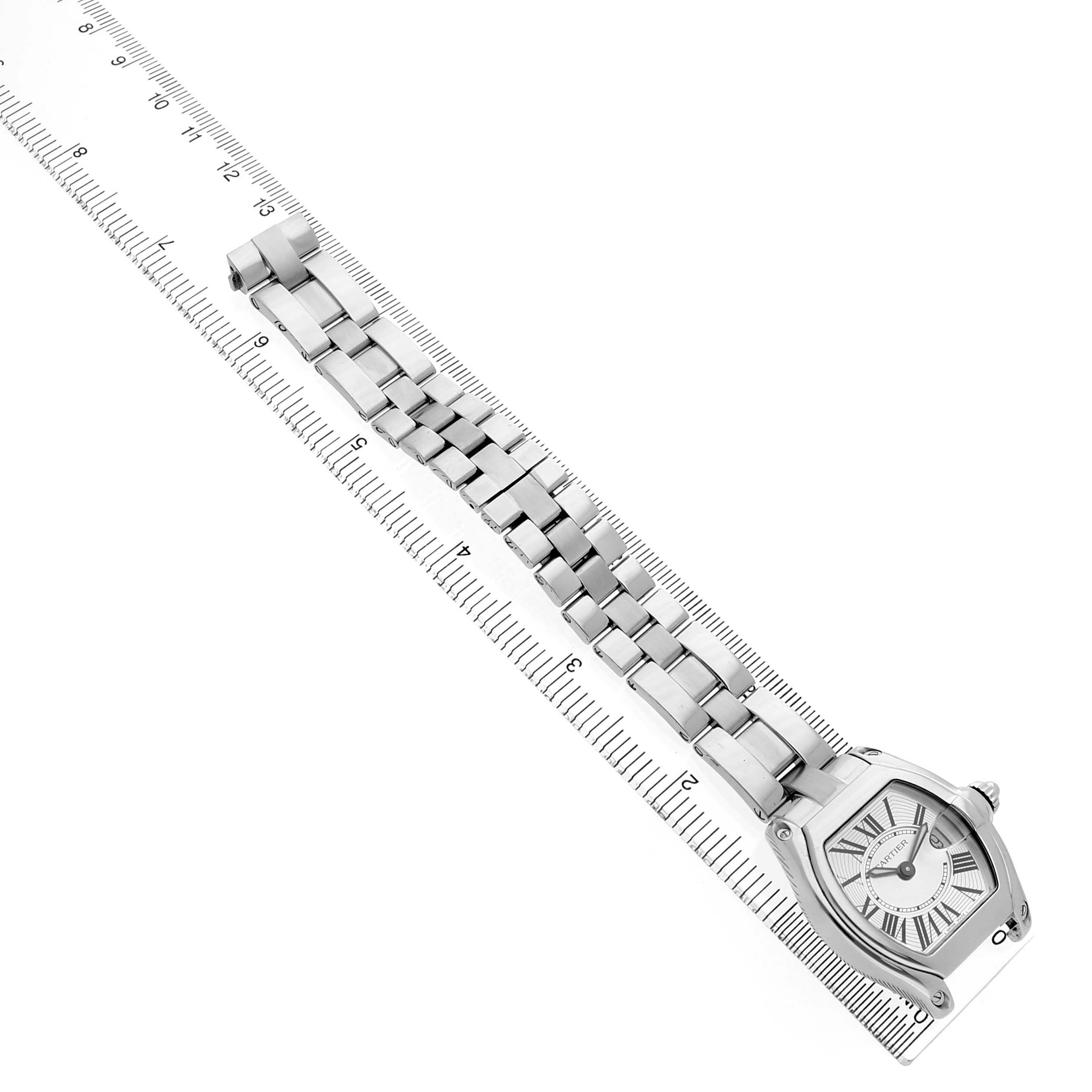 The Cartier Roadster W62016V3 Women's Stainless Steel Silver Dial watch is photographed from a top-down angle with its full band displayed alongside a ruler.