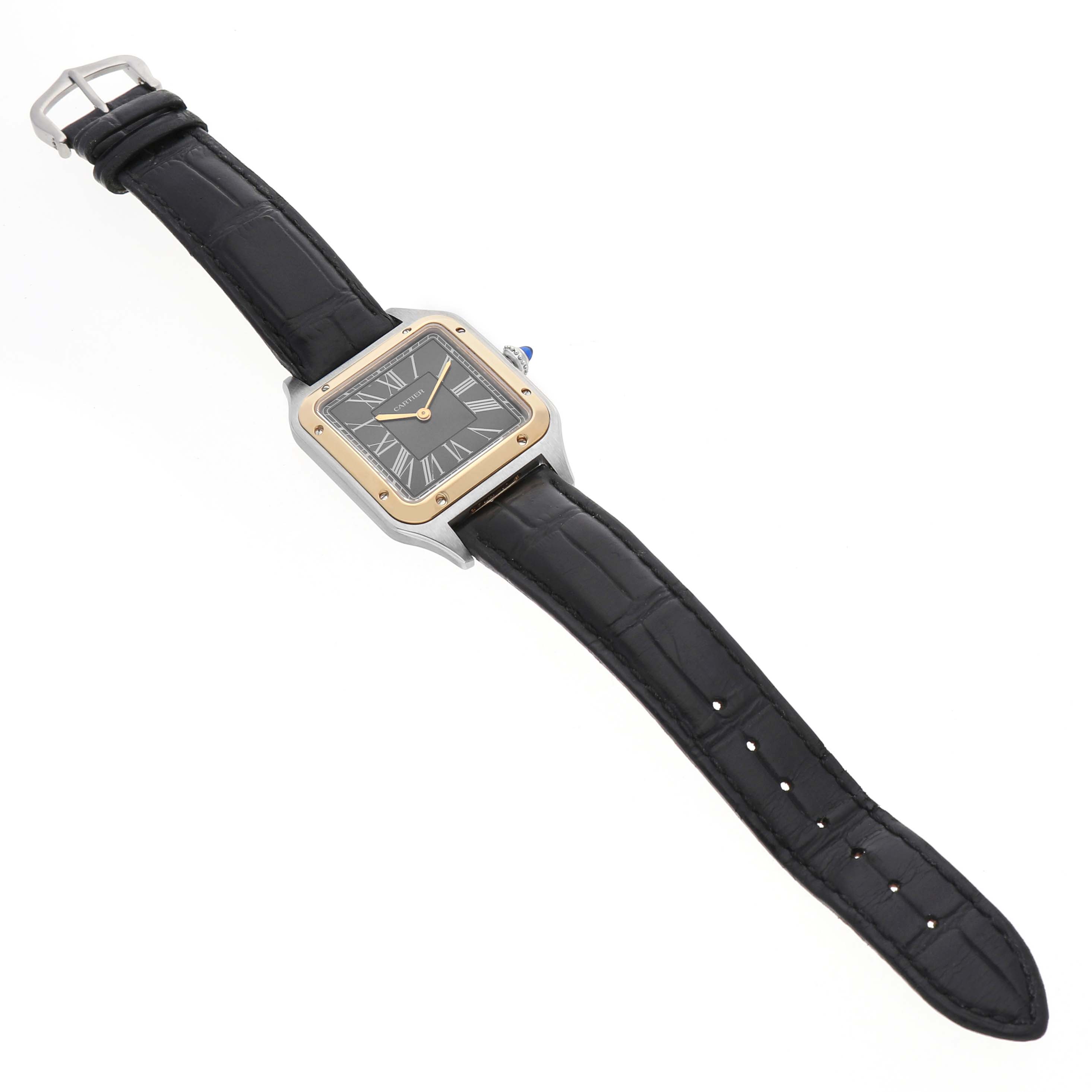 The Cartier Santos Dumont W2SA0015 Men's Steel and Gold (two tone) Black Dial watch is shown from a top-down angle, displaying the square face, crown, and black strap.