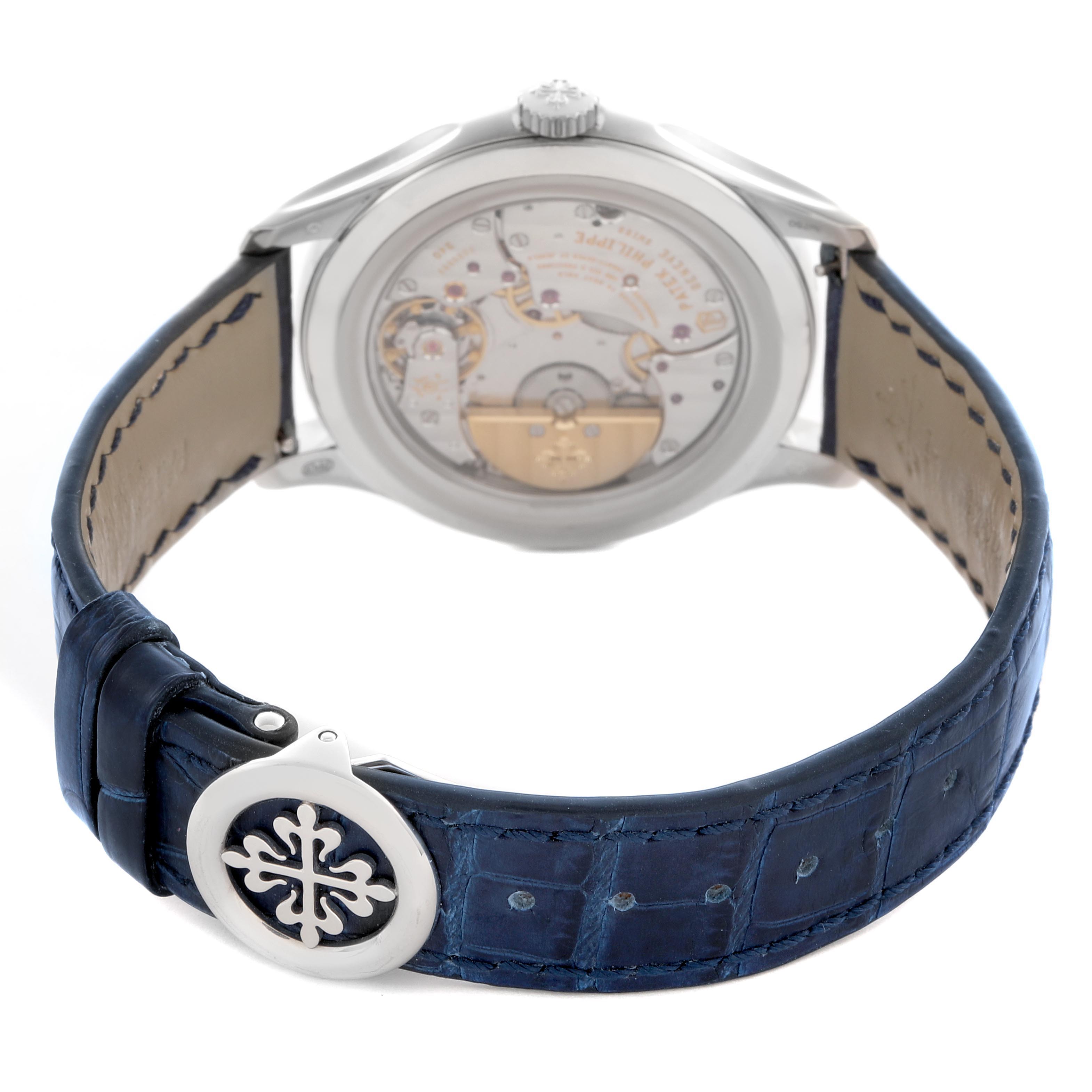 The image shows the back of a Patek Philippe Complications 5327G-001 Men's White Gold Blue Dial 5327G-001 Men's White Gold Blue Dial watch, revealing the movement, with a blue leather strap featuring the brand's logo.