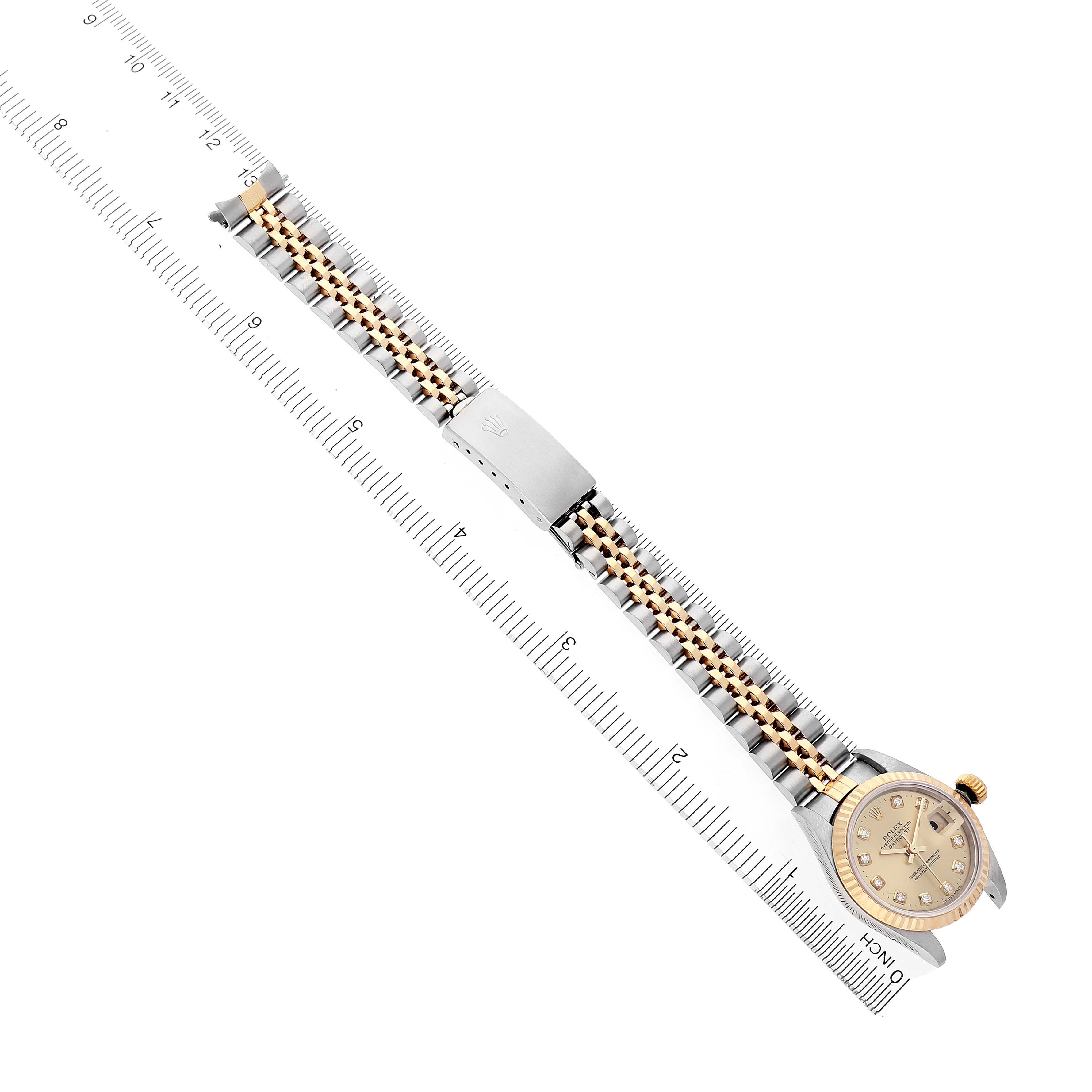 The Rolex Datejust 69173 Women's Steel and Gold (two tone) Champagne Dial watch is shown from a top view, highlighting the face, crown, bracelet, and clasp beside a ruler.