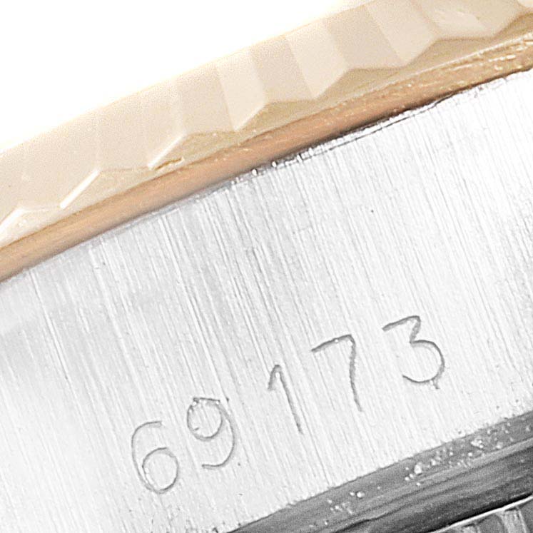 This close-up image of a Rolex Datejust 69173 Women
s Steel and Gold (two tone) Champagne Dial 69173 Women
s Steel and Gold (two tone) Champagne Dial watch shows the fluted bezel and part of the case with its engraved serial number.