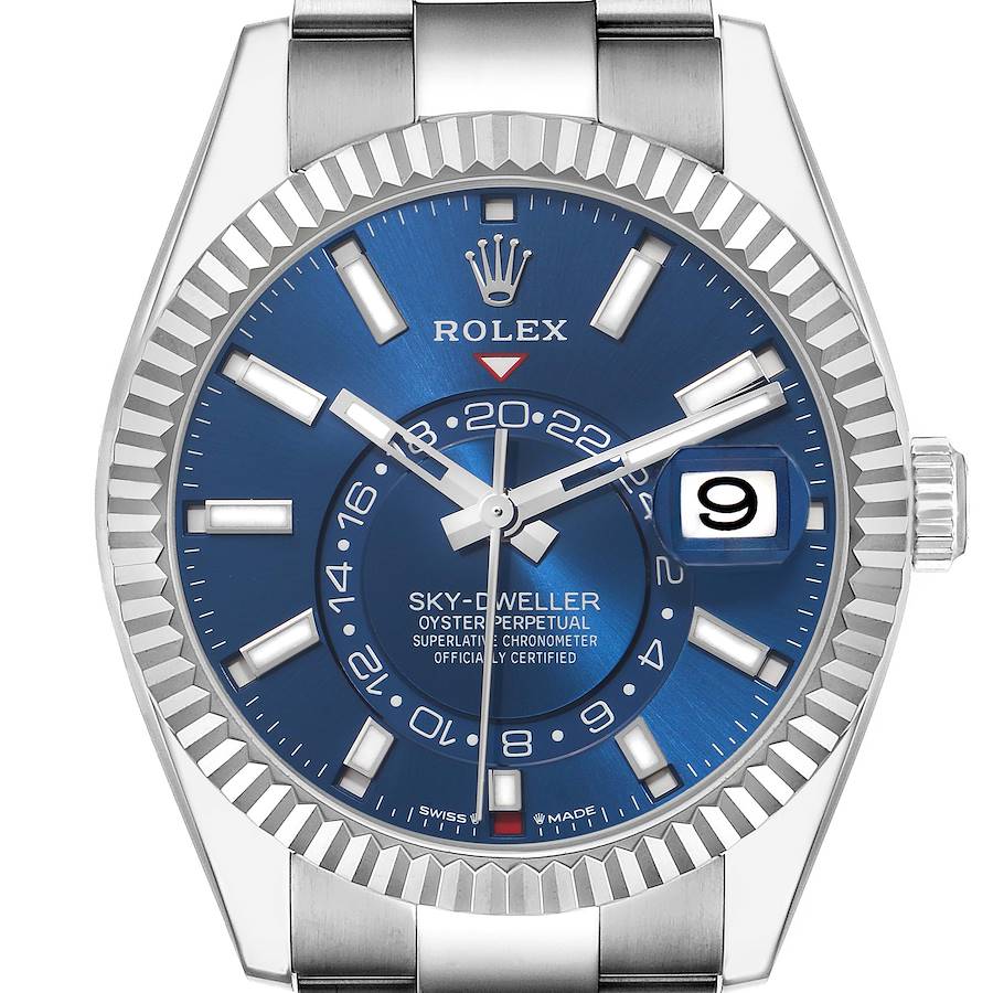 The Rolex Sky-Dweller is shown from the front, highlighting its blue dial, fluted bezel, date window, and silver hands.