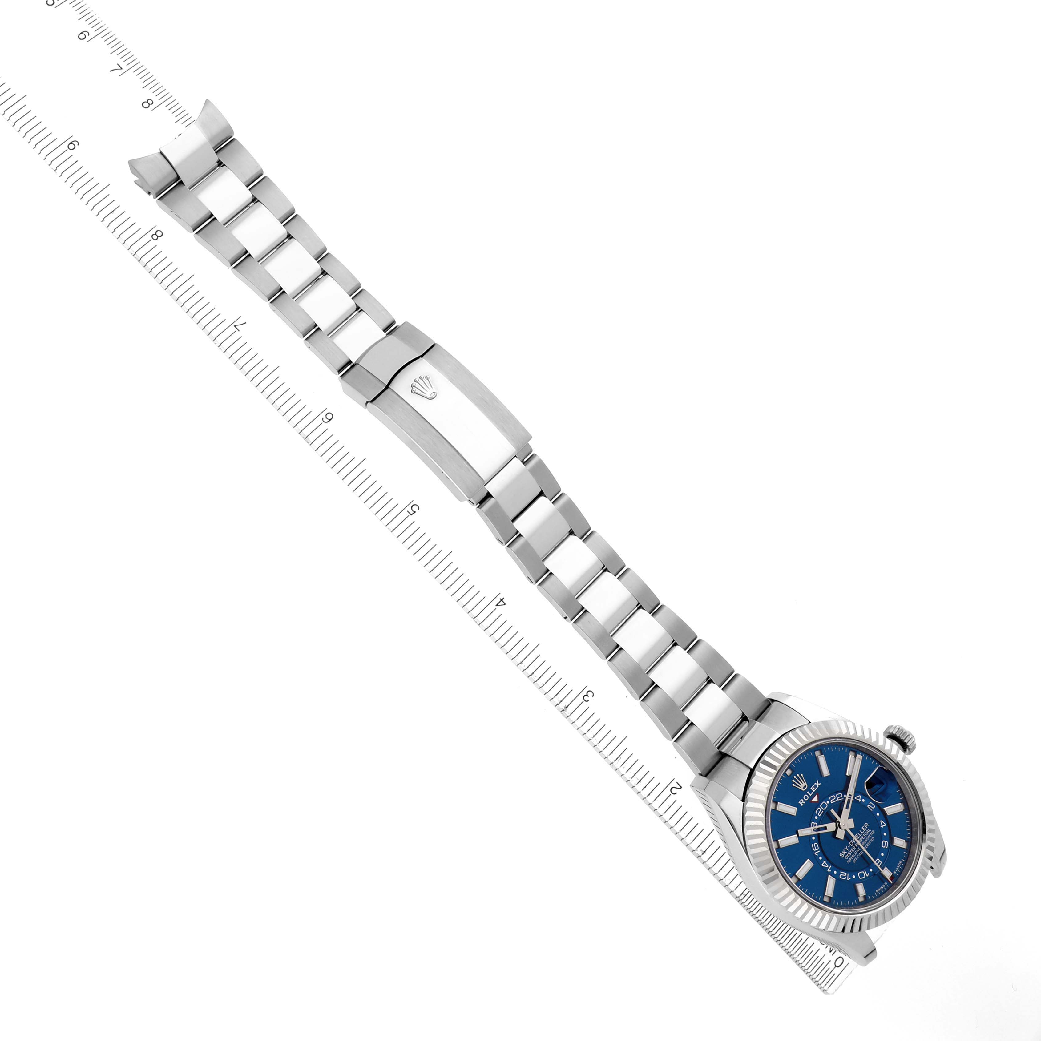 The Rolex Sky-Dweller 336934 Men's Stainless Steel Blue Dial 336934 Men's Stainless Steel Blue Dial is shown at an overhead angle, displaying its full bracelet and face, positioned next to a ruler.