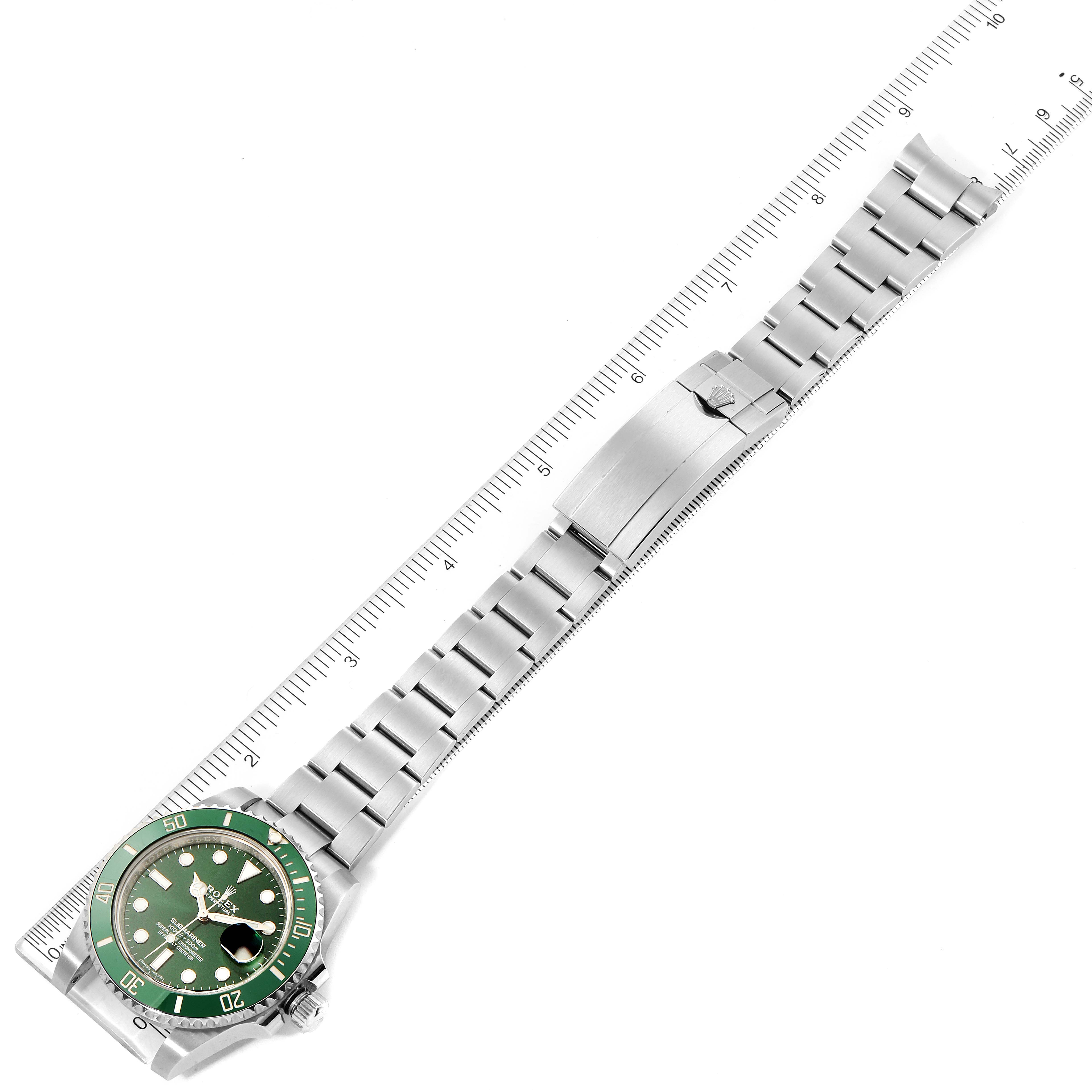 The image shows the Rolex Submariner 116610LV Men
s Stainless Steel Green Dial 116610LV Men
s Stainless Steel Green Dial watch laid flat, with the face, bezel, bracelet, and clasp visible, alongside a ruler.