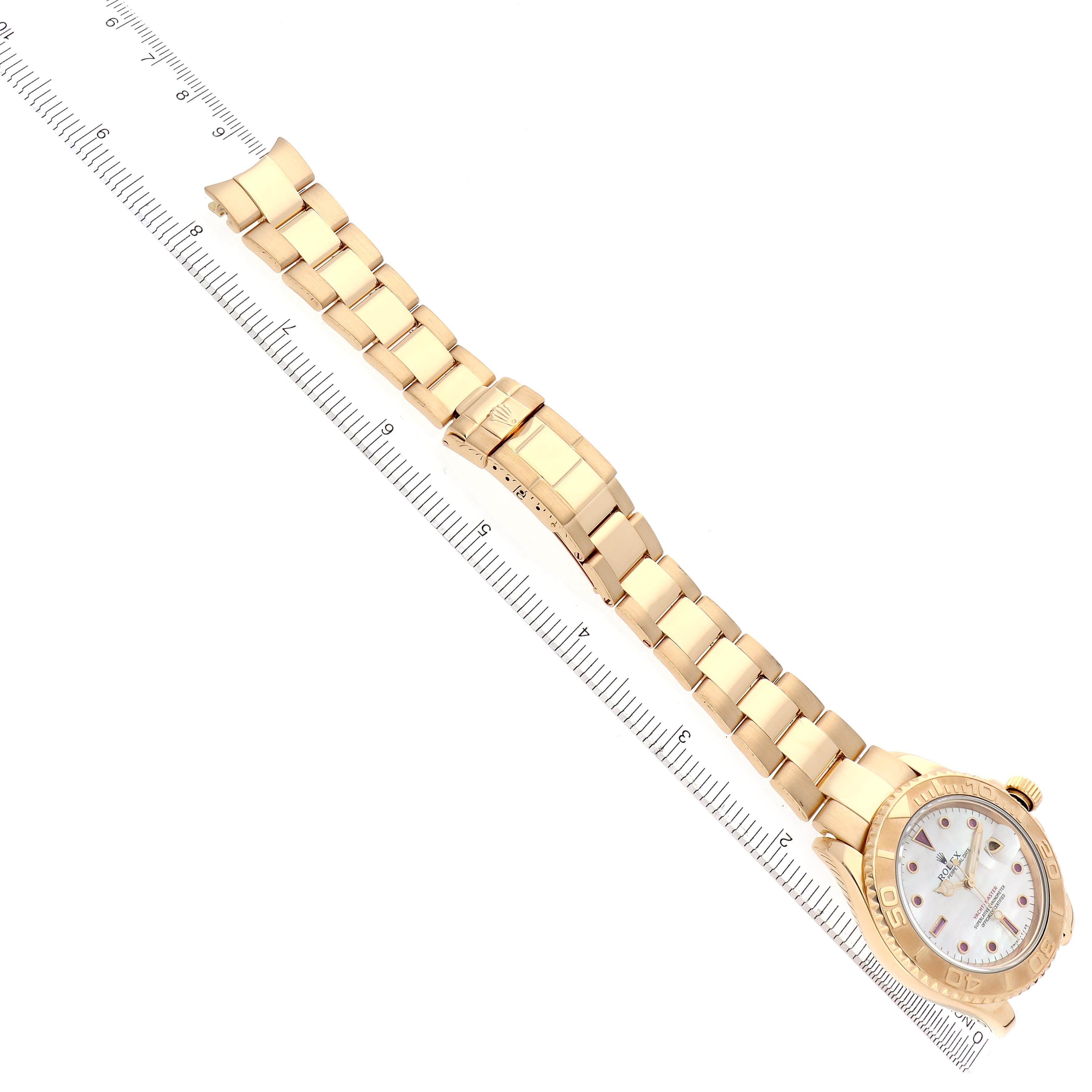 The Rolex Yacht-Master 16628 Men's Yellow Gold Mother of Pearl Dial 16628 Men's Yellow Gold Mother of Pearl Dial watch is shown from an overhead angle, displaying the bracelet, clasp, and face with a ruler for scale.