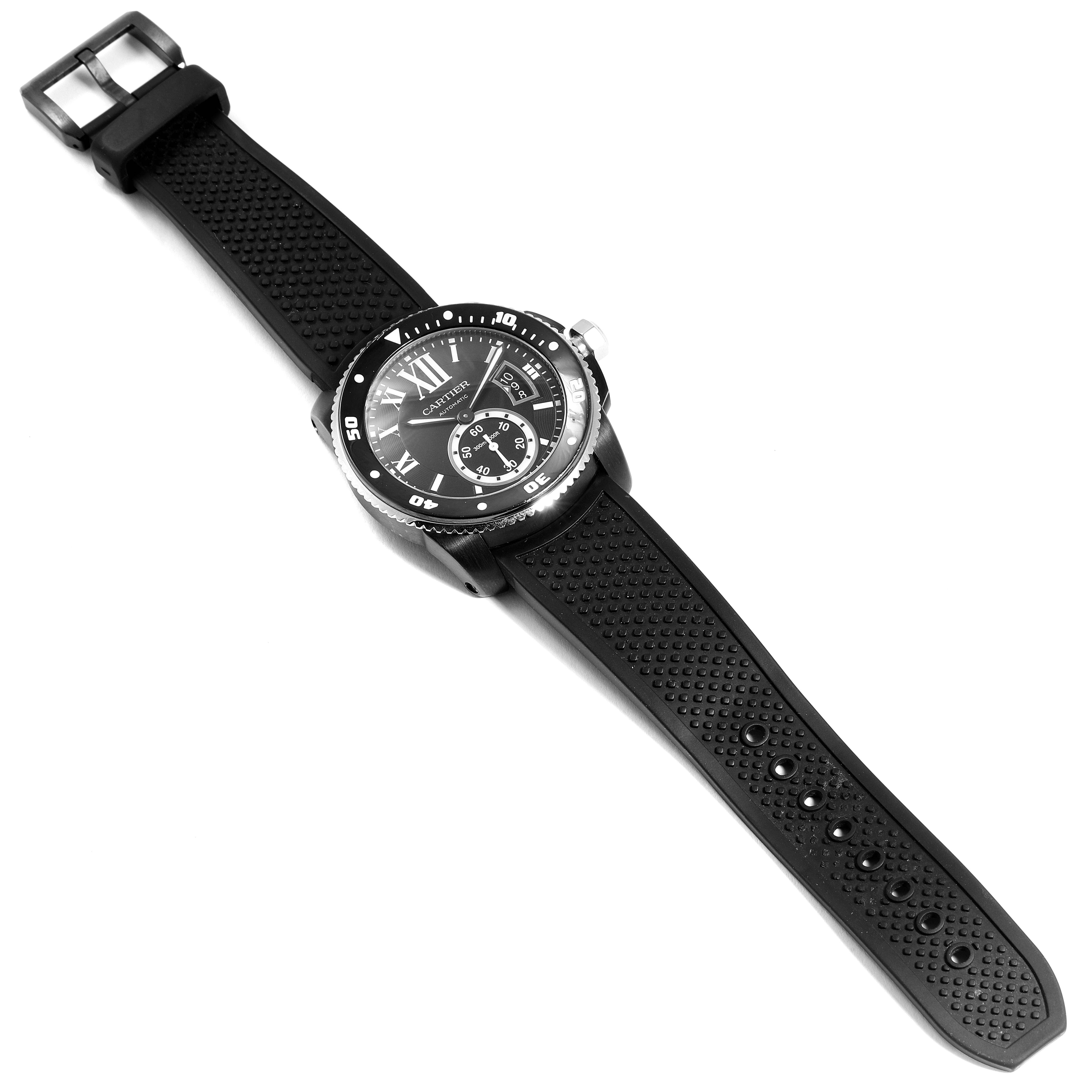 The image shows the Cartier Calibre de Cartier WSCA0006 Men's Stainless Steel Black Dial WSCA0006 Men's Stainless Steel Black Dial watch from a top-down angle, displaying its face, bezel, and rubber strap.