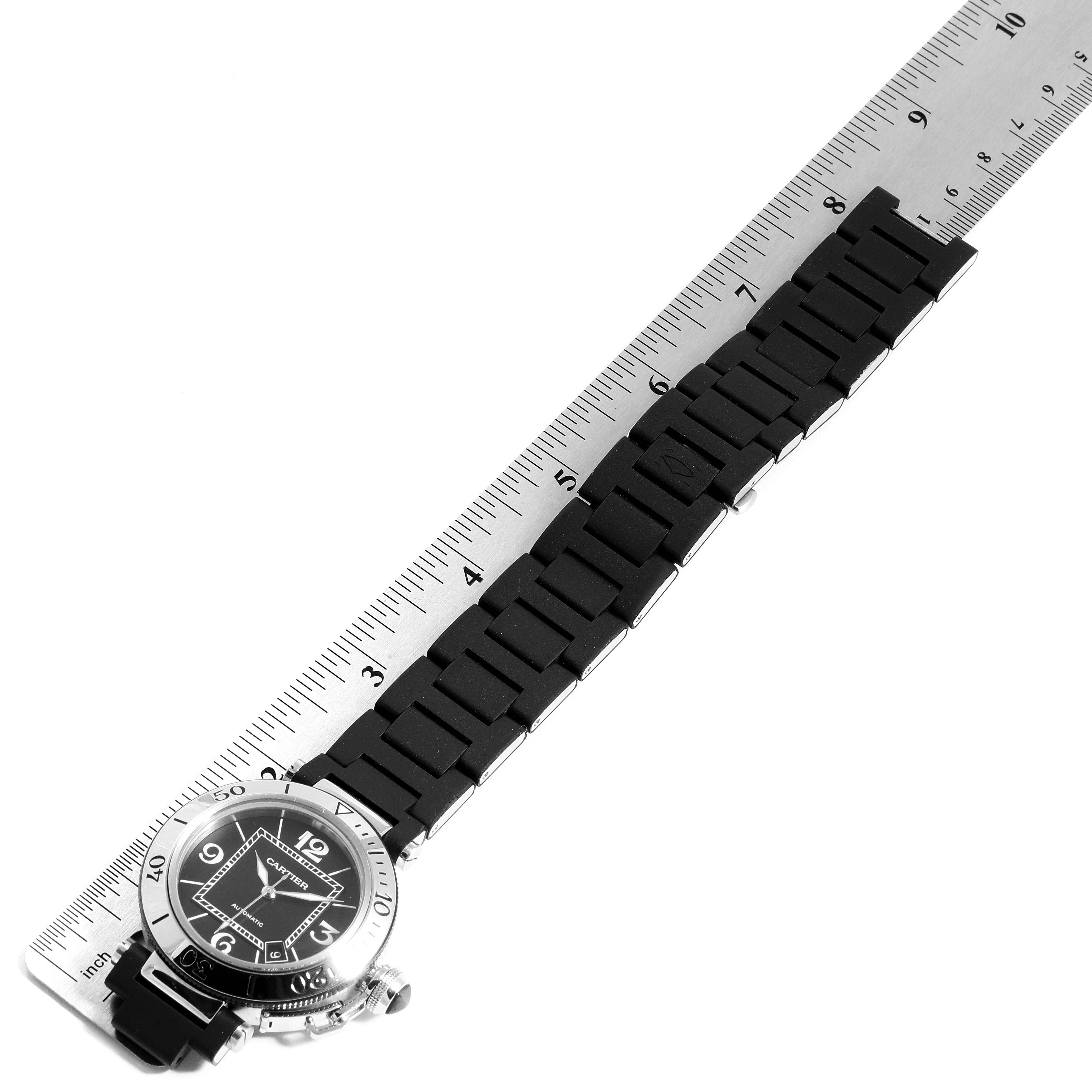 The Cartier Pasha W31088U2 Men's Stainless Steel Black Dial W31088U2 Men's Stainless Steel Black Dial watch is shown from a top-down angle, emphasizing its face and black strap alongside a ruler for scale.