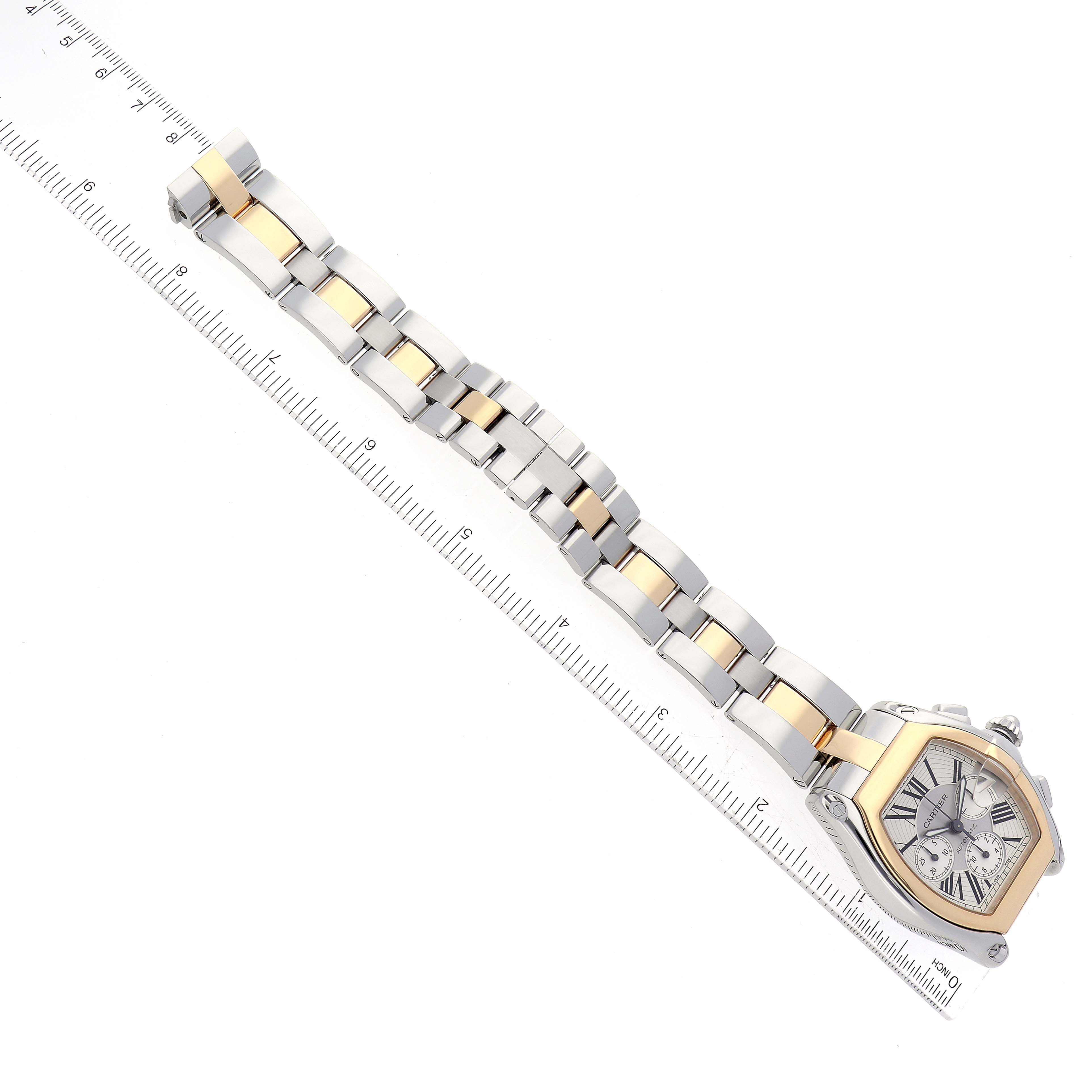 This image shows the front angle of a Cartier Roadster W62027Z1 Men
s Steel and Gold (two tone) Silver Dial W62027Z1 Men
s Steel and Gold (two tone) Silver Dial watch with its bracelet aligned next to a ruler for scale.