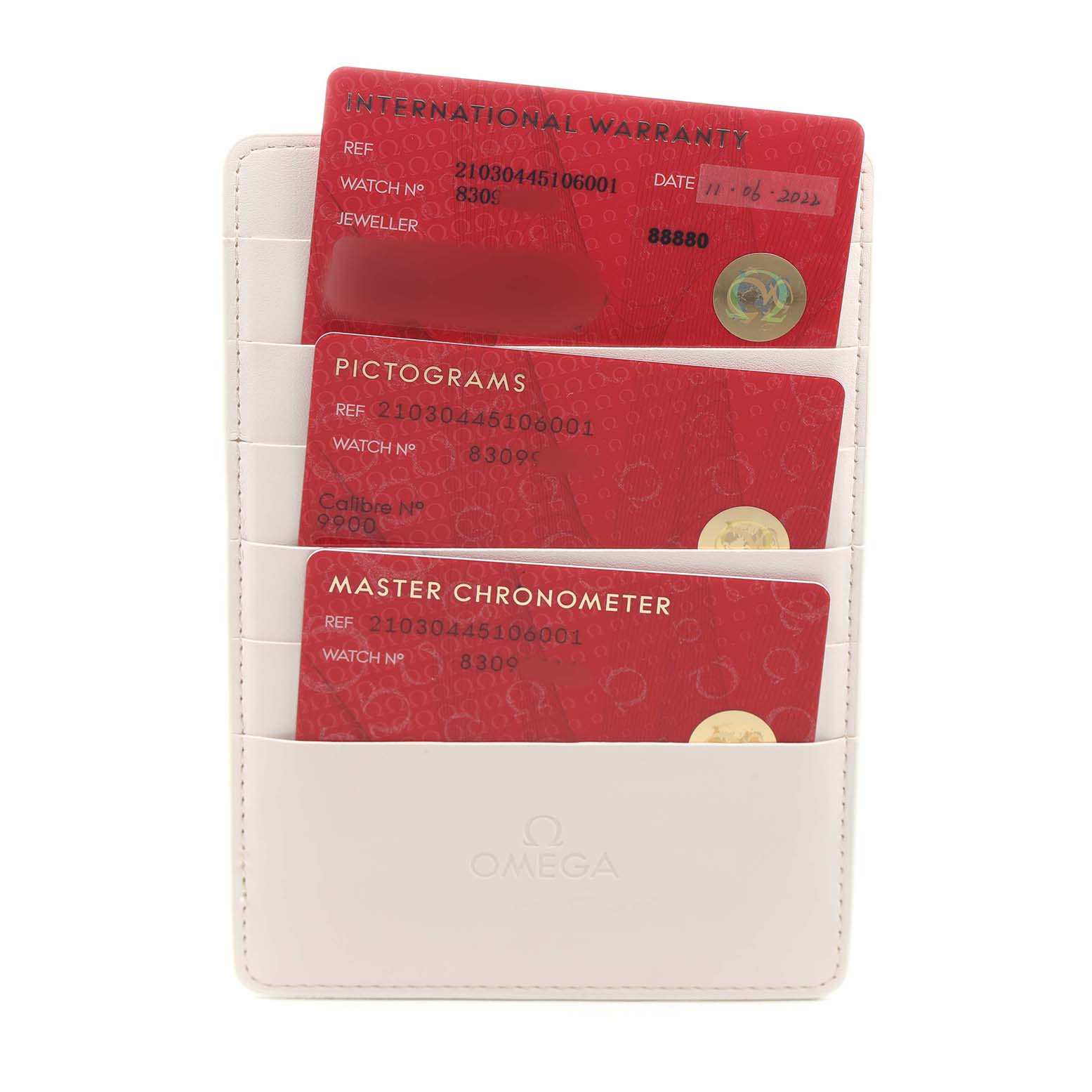The image shows a set of red cards, including an International Warranty, Pictograms, and Master Chronometer, in a white Omega cardholder for the Seamaster model.