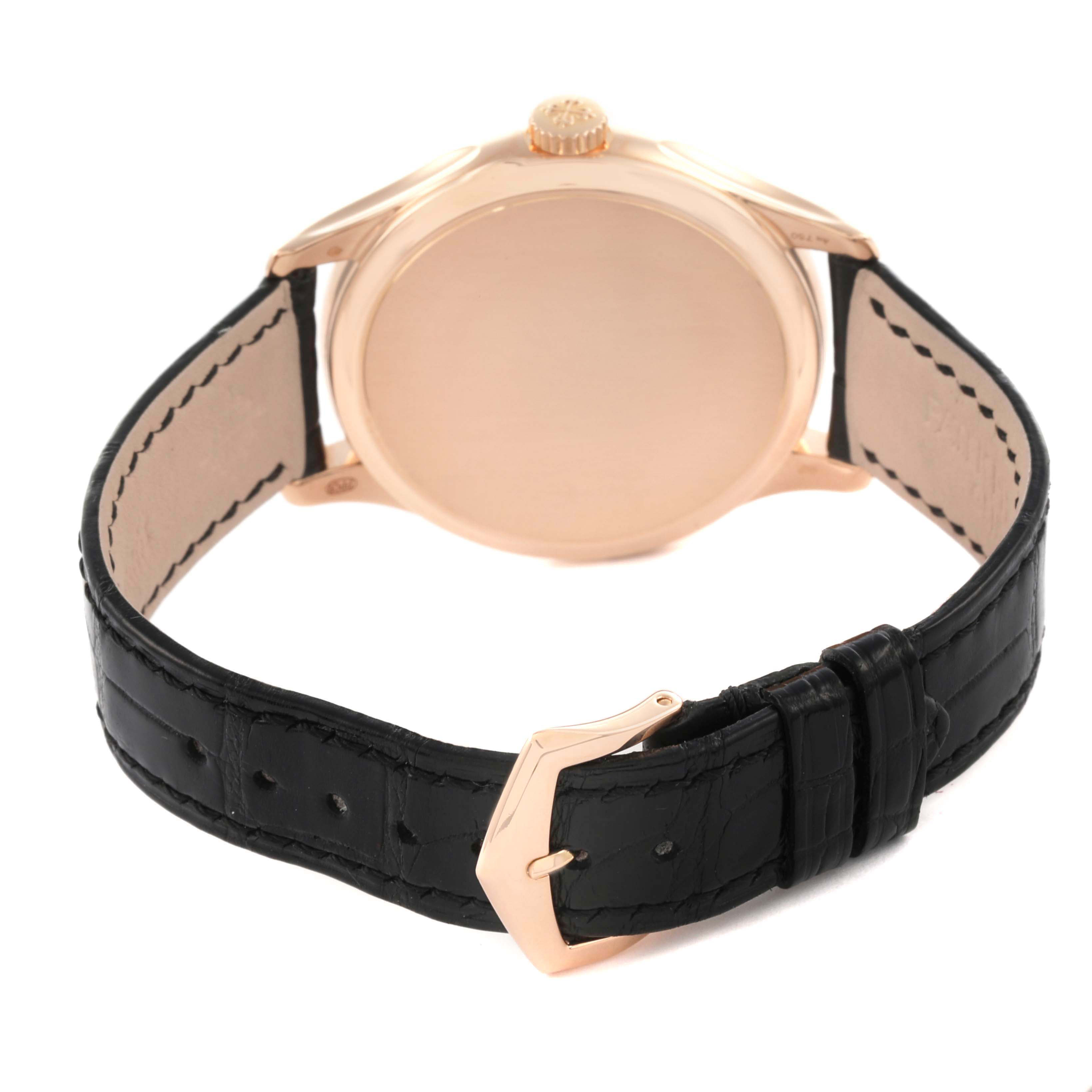 The Patek Philippe Calatrava 5227R Men's Rose Gold Beige Dial watch is shown from the back, highlighting the case back, crown, and black leather strap with buckle.